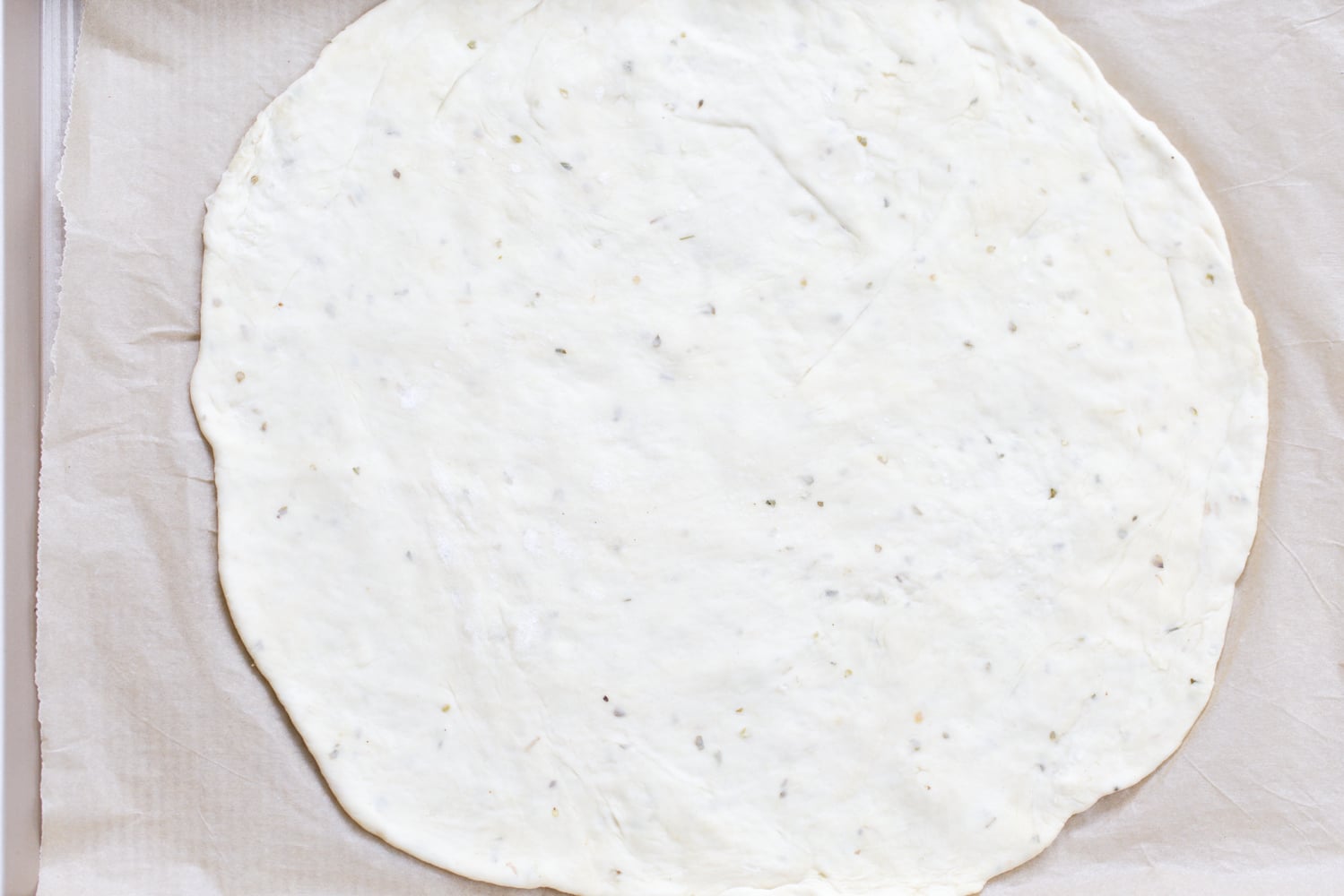 yeast free pizza dough rolled out pizza dough on parchment paper
