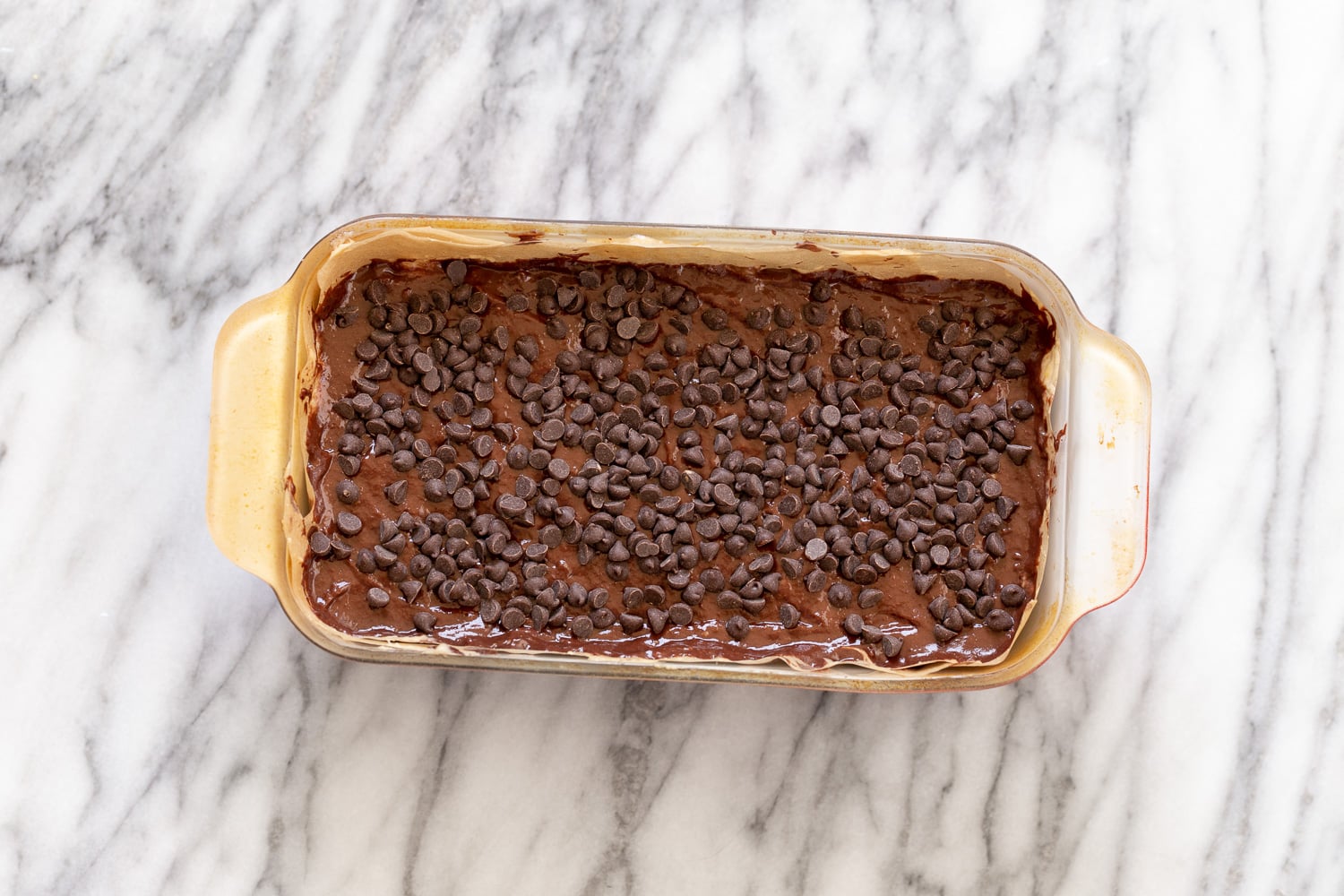 chocolate banana bread chocolate banana bread batter being topped with vegan chocolate chips for making banana bread