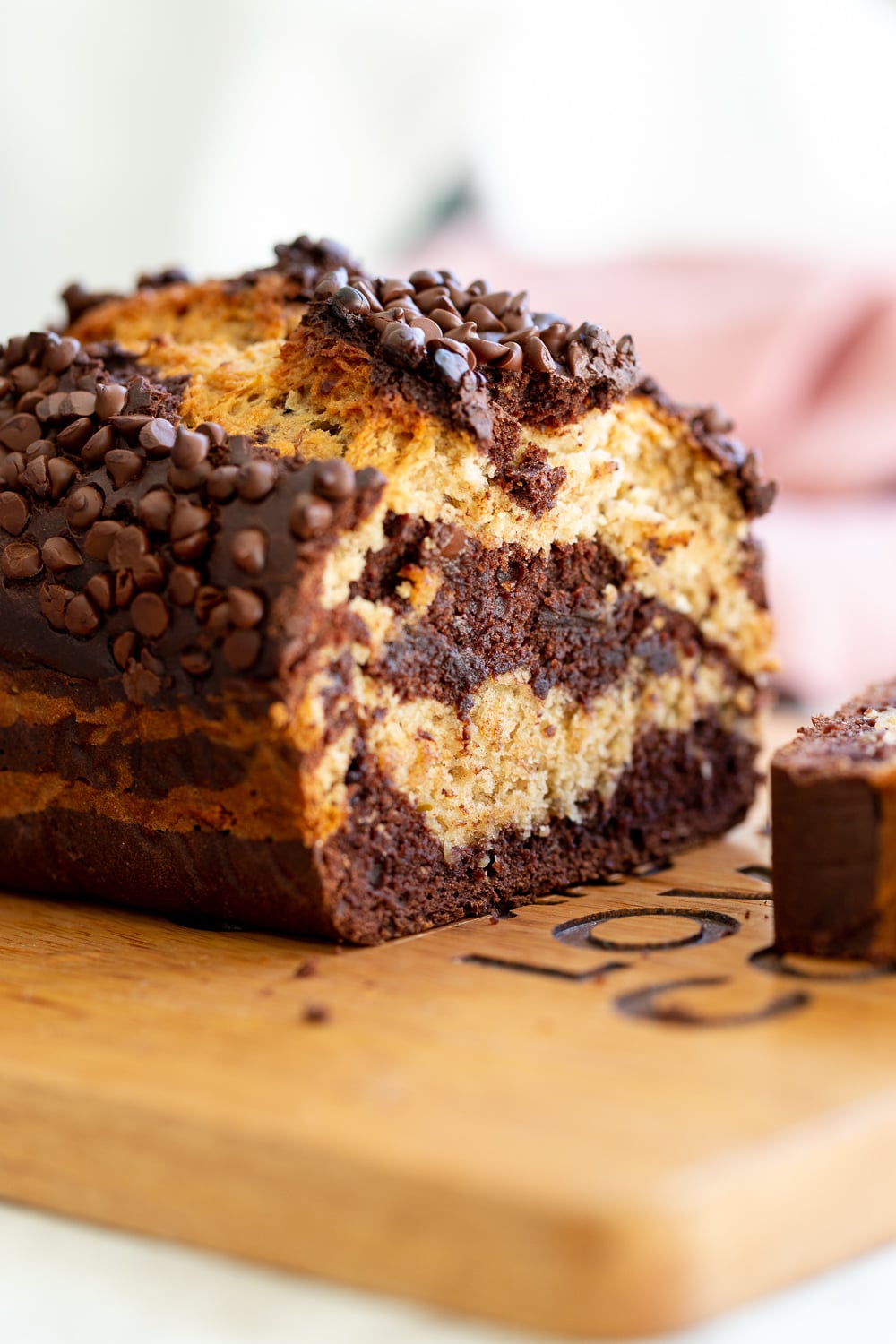 chocolate banana bread a sliced loaf of marbled vegan chocolate banana bread topped with chocolate chips on a cutting board