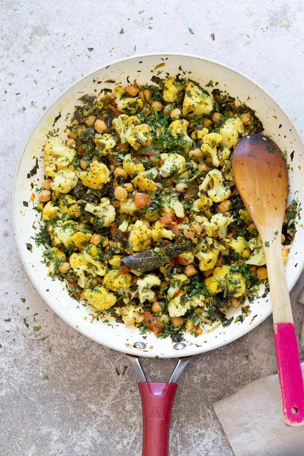 overhead shot of a pan with cauliflower, chickpeas and spinach sauteed with Indian spices