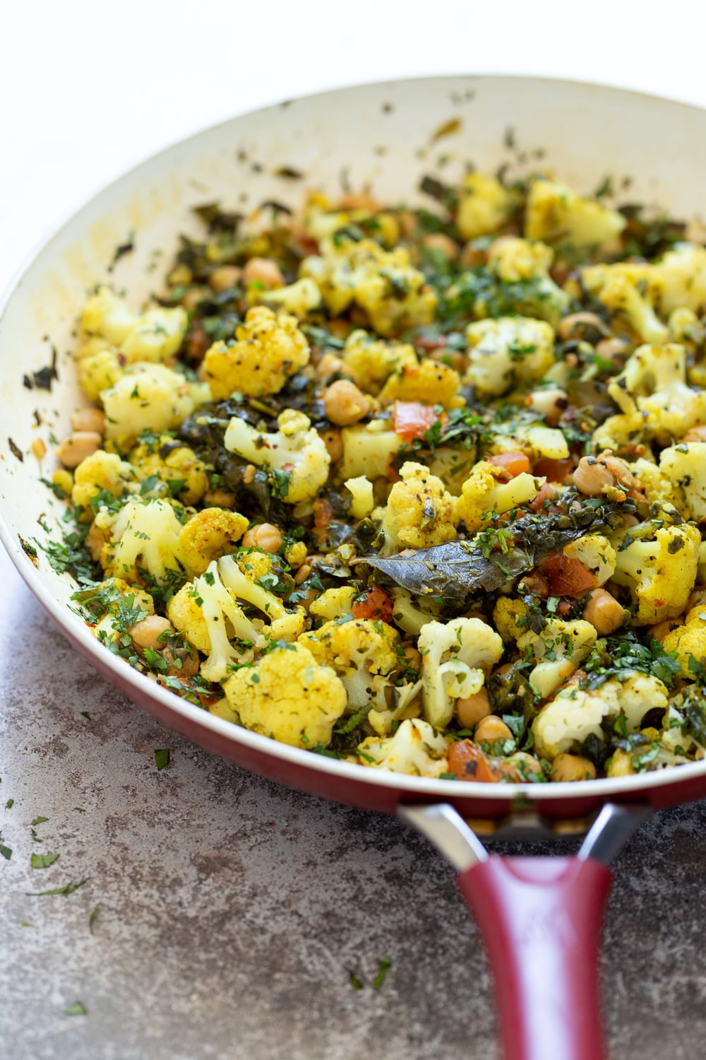 chickpeas and spinach side view of a pan with cauliflower, chickpeas and spinach sauteed with Indian spices
