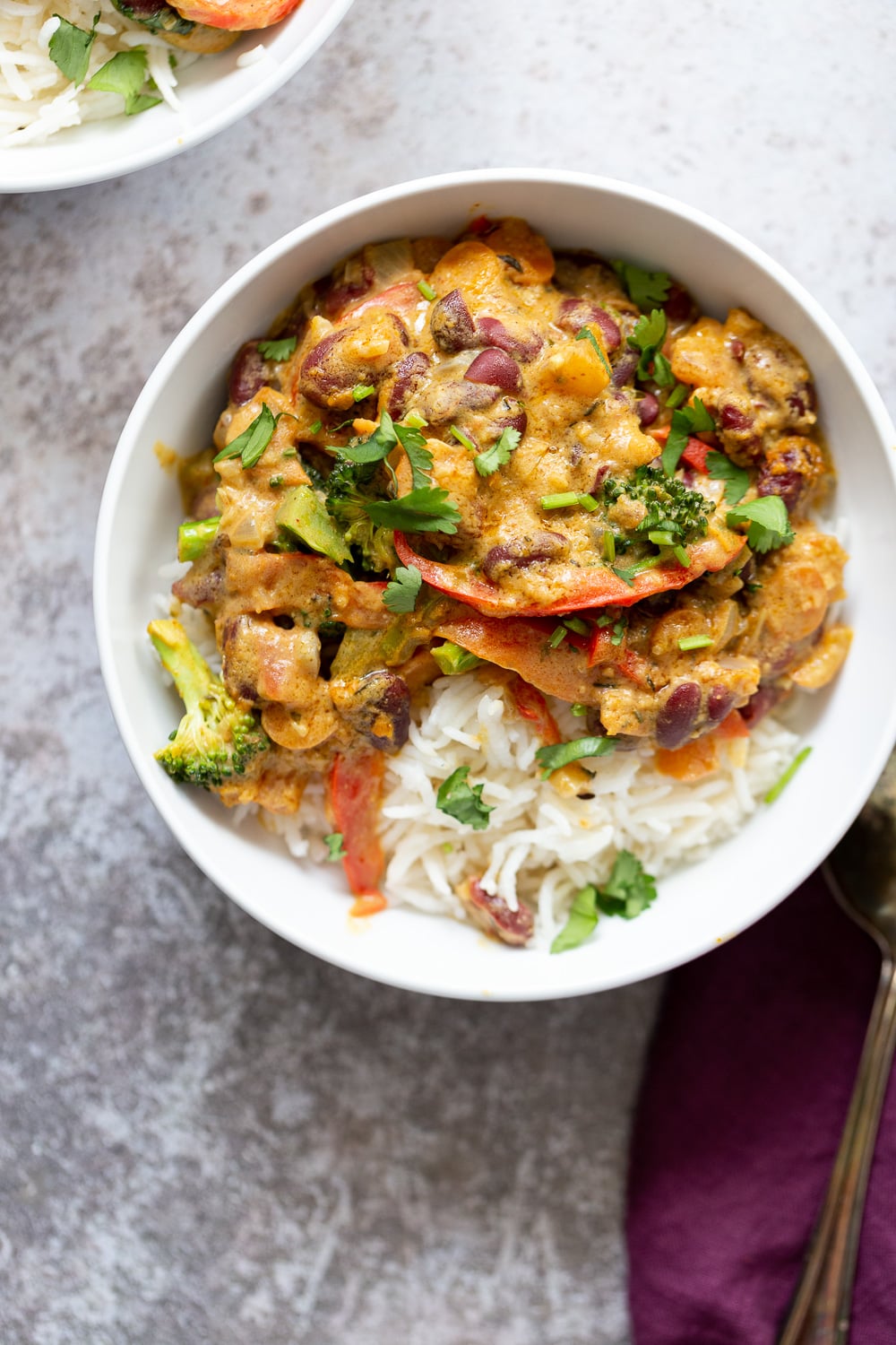 overhead shot of a bowl of creamy vegan coconut peanut stew with veggies and kidney beans served over rice