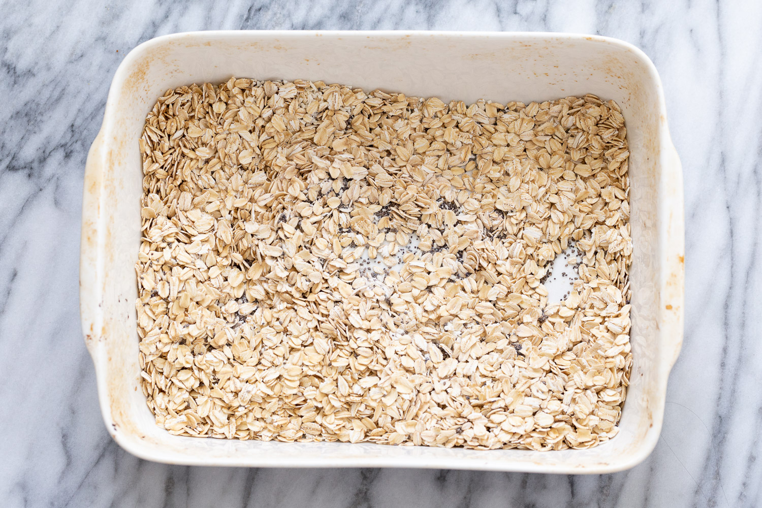 overhead shot of a casserole dish filled with rolled oats and chia seeds 