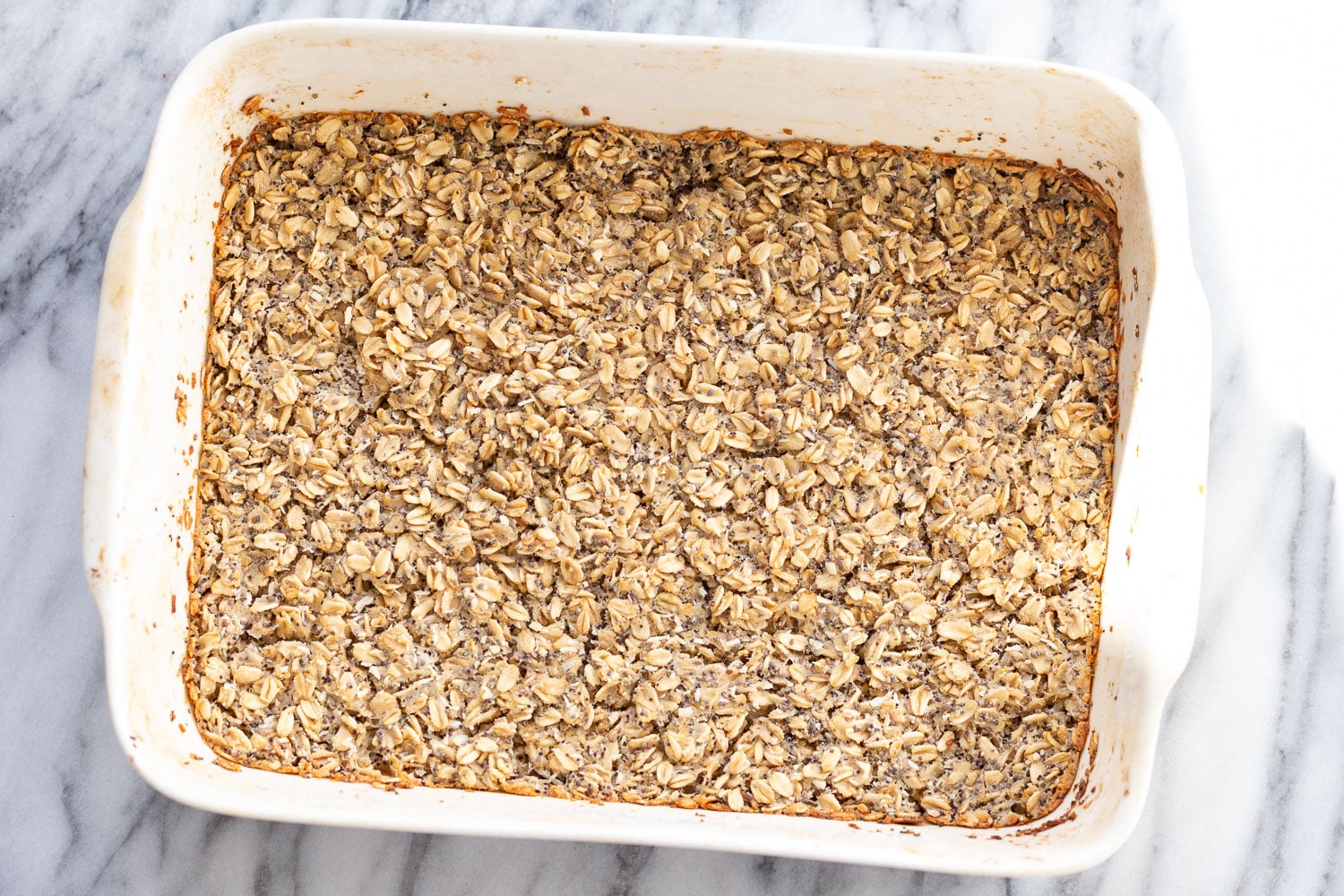 overhead shot of freshly baked vegan baked poppyseed and lemon oatmeal in a white casserole dish