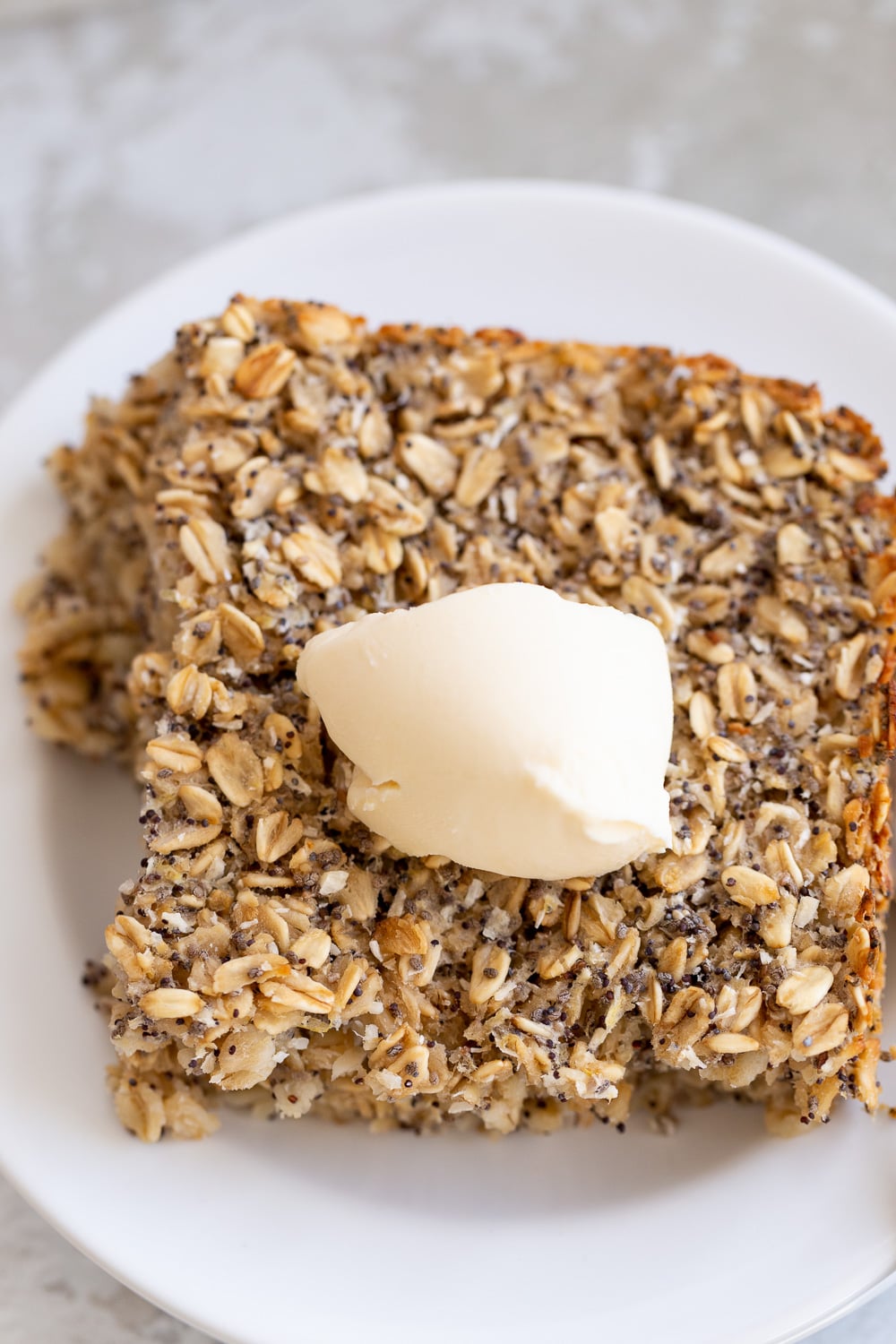 overhead shot of a square of healthy vegan baked poppyseed lemon oatmeal topped with coconut whipped cream 