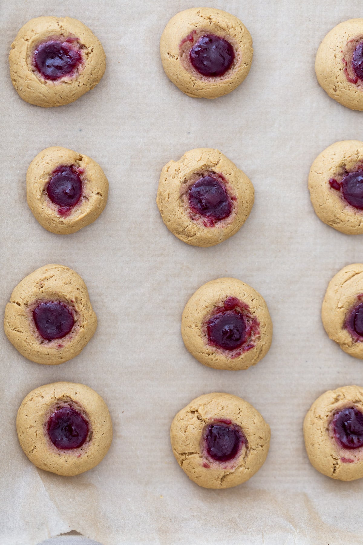 thumbprint cookies overhead shot of a cookie tray with freshly baked pb&j thumbprint cookies
