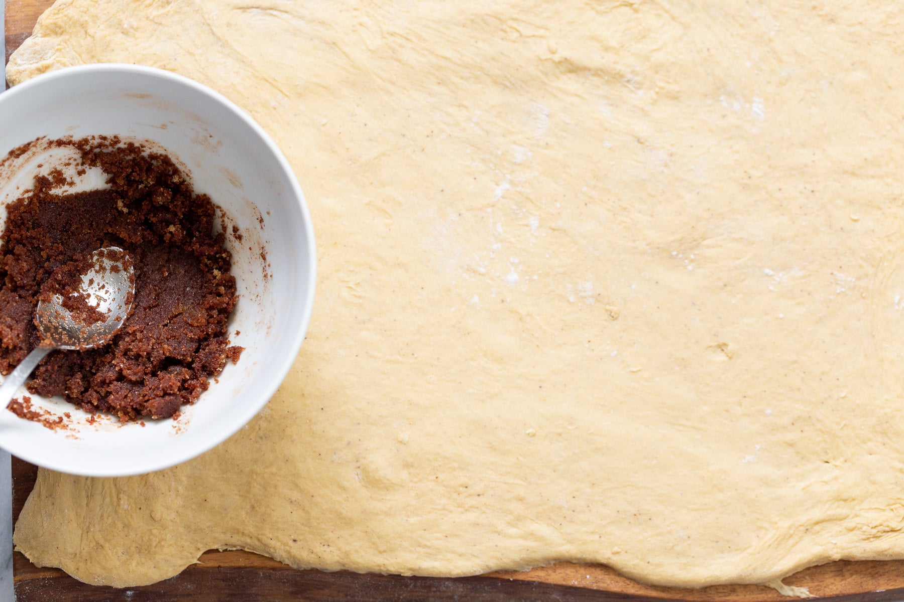 no yeast cinnamon rolls brown sugar cinnamon mixture being spread on top of no yeast cinnamon roll dough