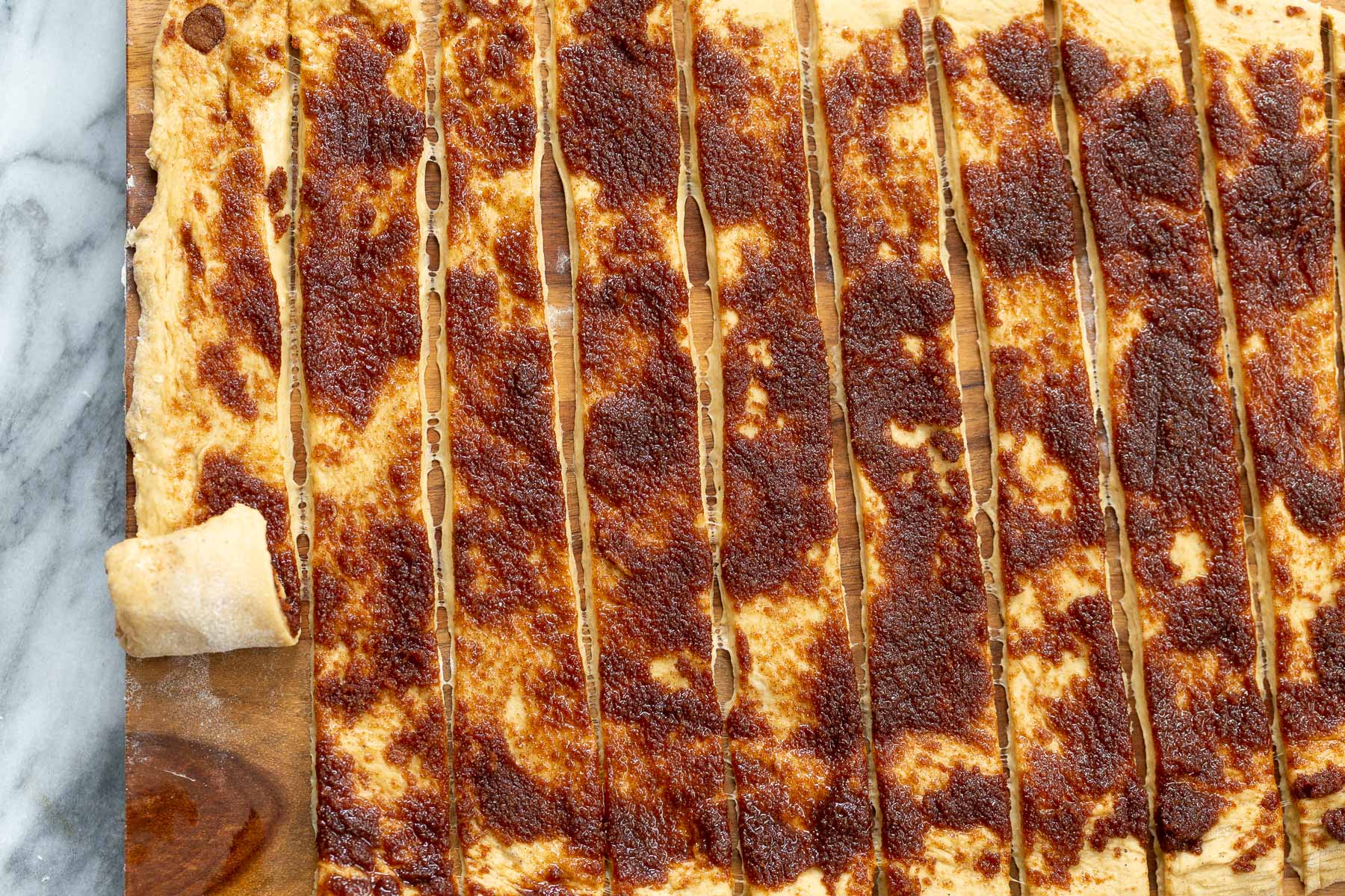 no yeast cinnamon rolls rolled out cinnamon rolls dough being cut into strips and rolled up into buns