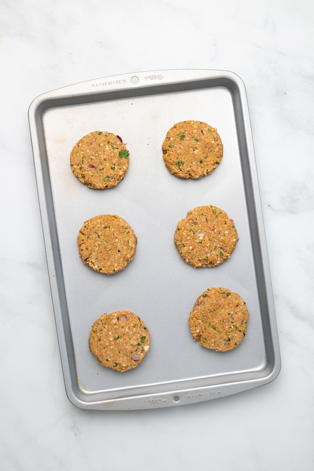 chickpea burger overhead shot of vegan chickpea burger patties lined up on a cookie sheet