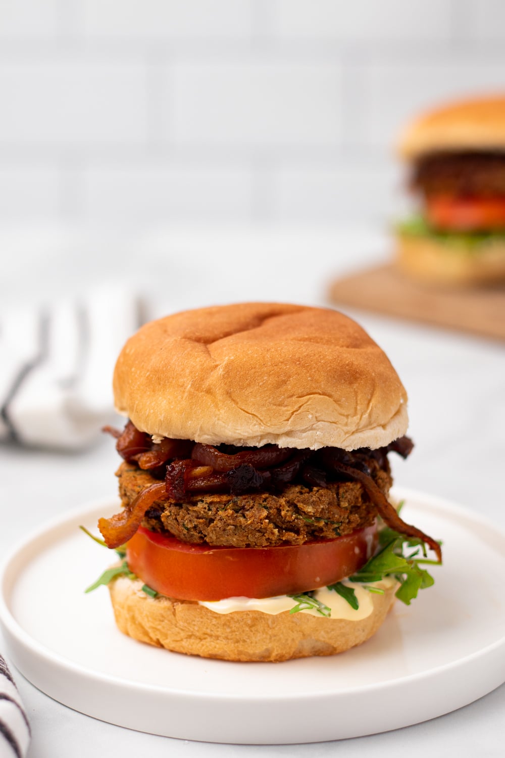 chickpea burger side view of a Middle Eastern Za'atar spiced chickpea burger with caramelized onion and hummus on a white plate