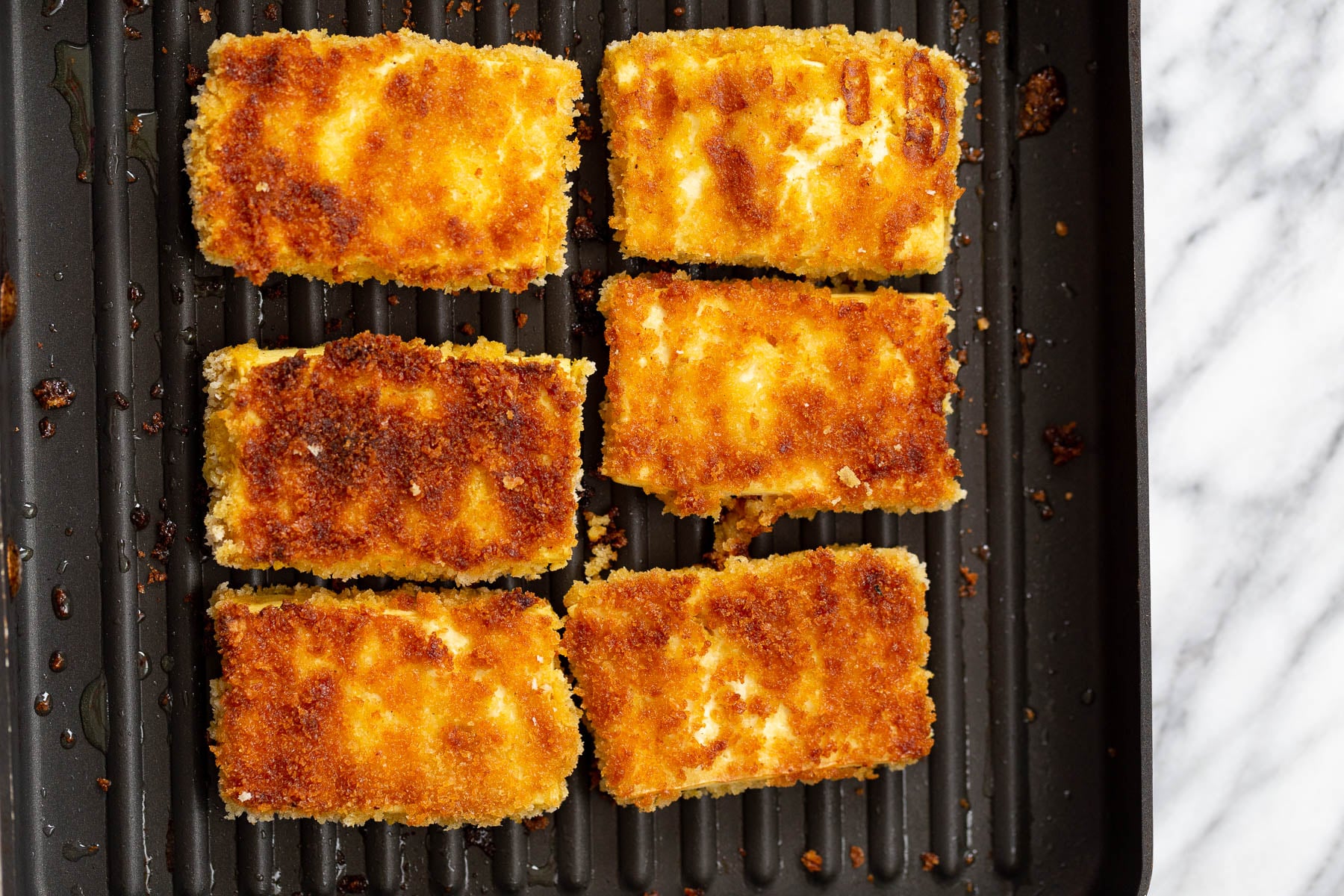 katsu curry breaded tofu sliced being fried in a grilling pan