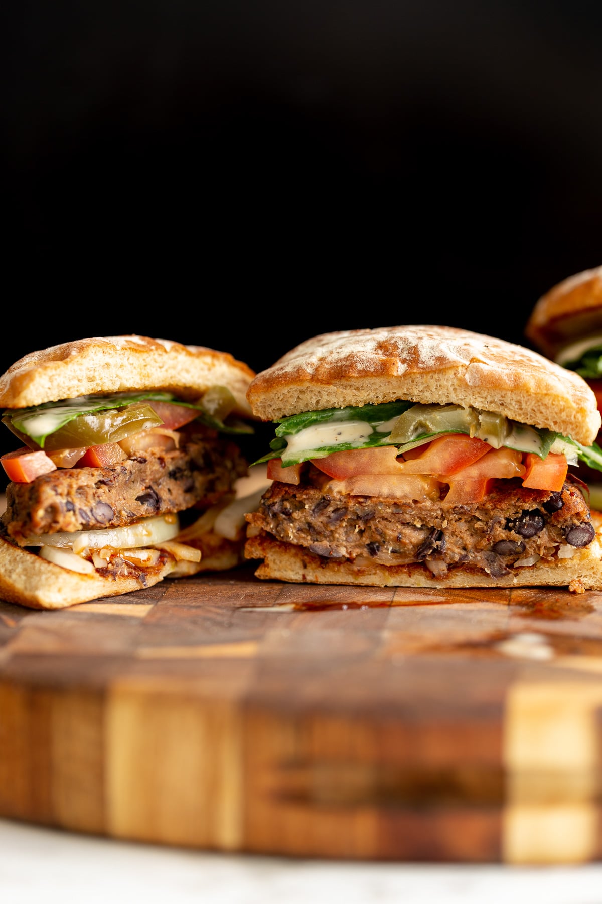 quinoa burger a halved vegan black bean quinoa burger topped with tomato slices and drizzled with ranch sauce