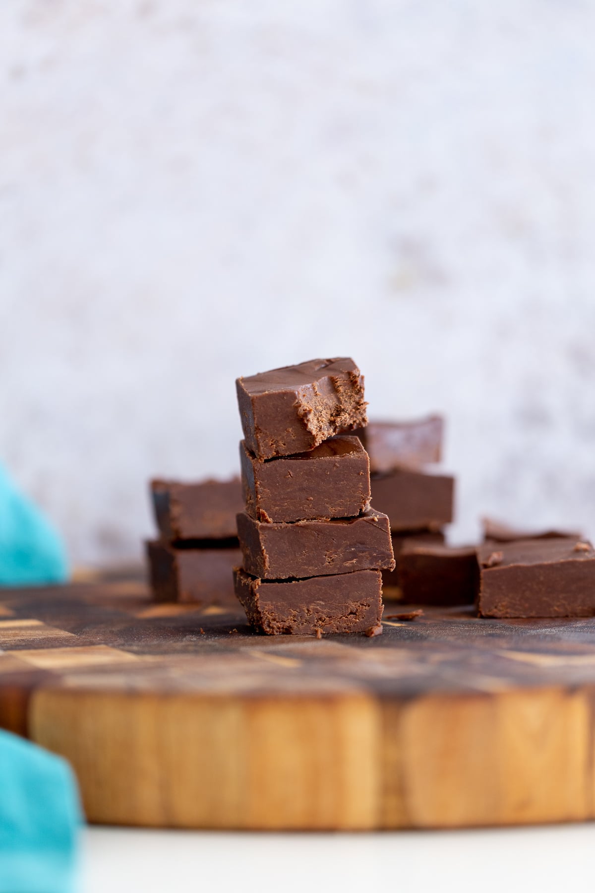 chocolate fudge recipe side view of a stach of vegan chocolate fudge on a wooden board