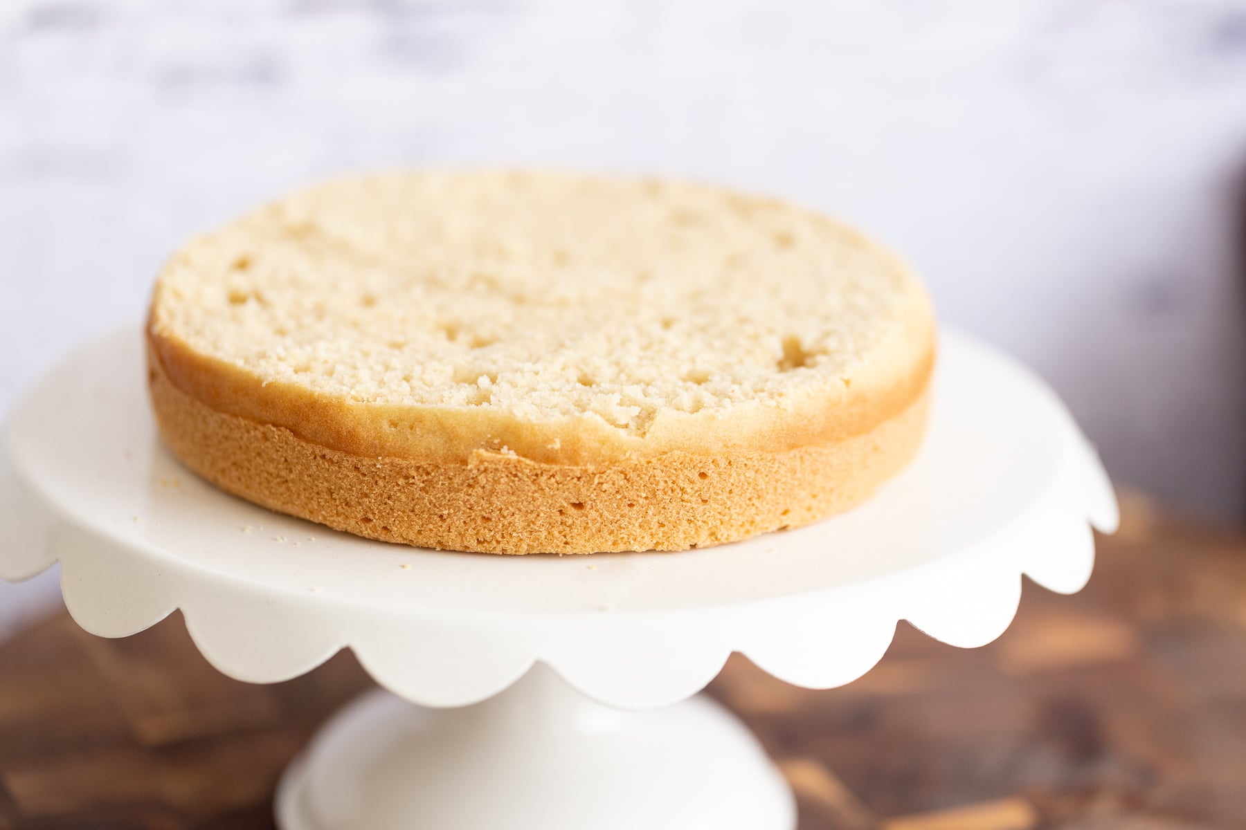 vegan white cake half a vegan white cake on a cake stand ready to be assembled into a layer cake