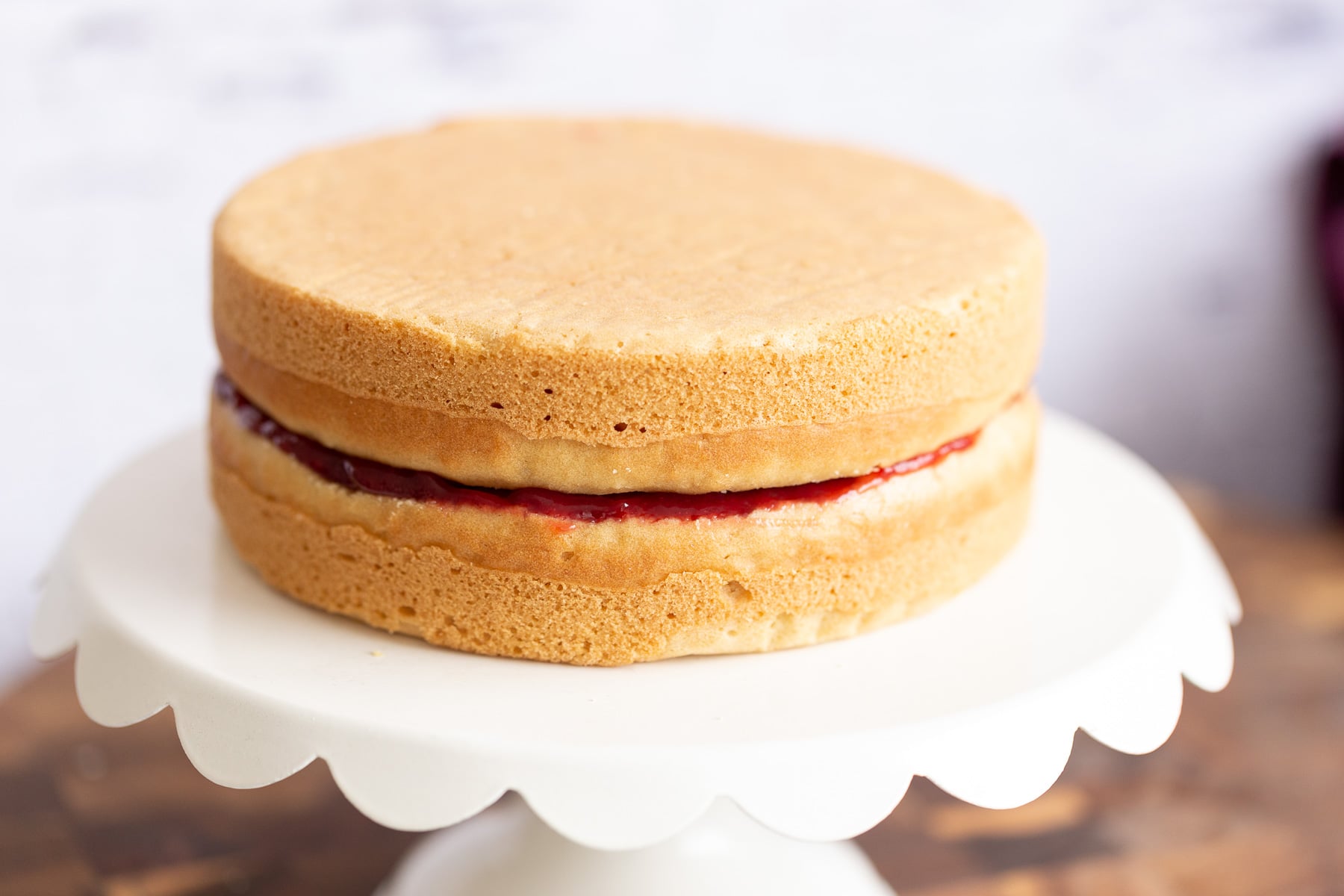 vegan white cake assembled vegan white cake filled with raspberry jam on a cake stand