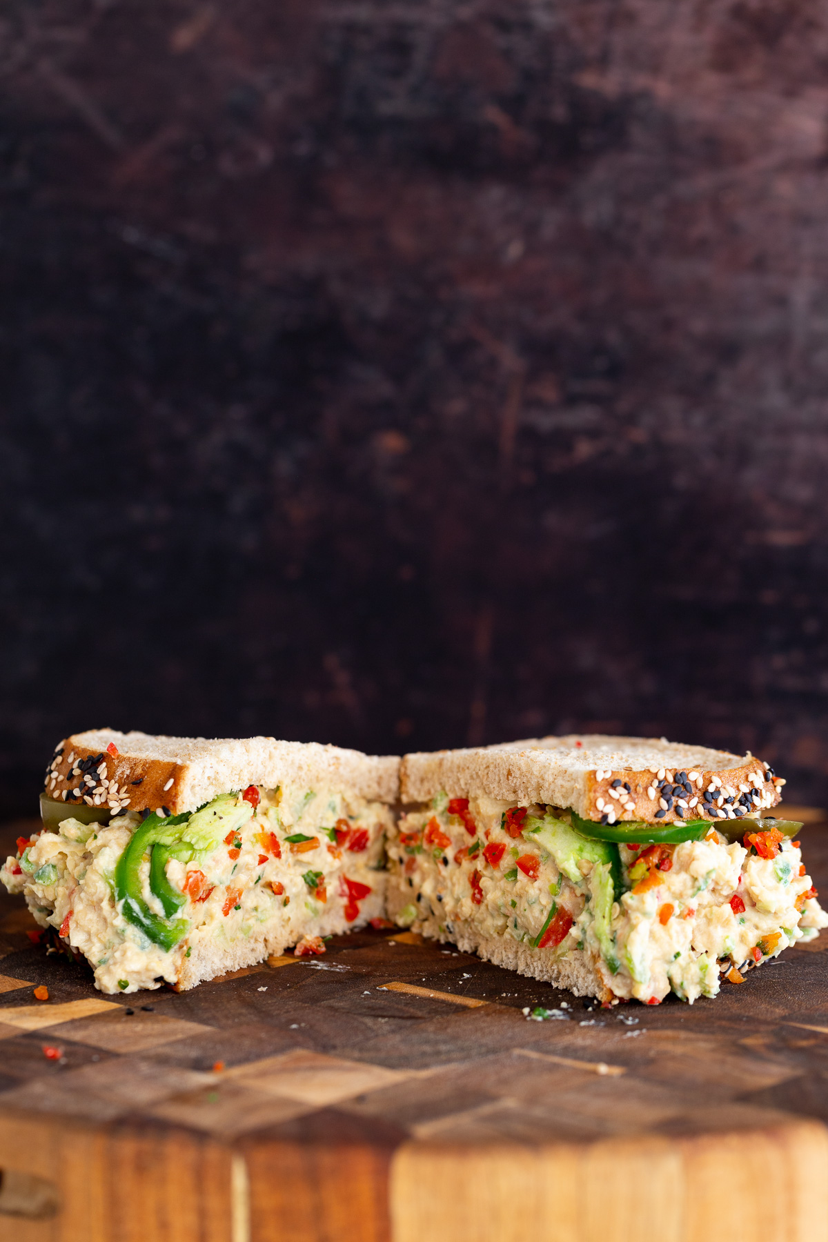 chickpea salad sandwich halfed vegan jalapeño popper chickpea salad sandwich on a wooden chopping board