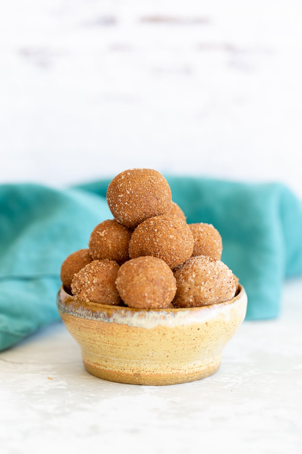 Snickerdoodle bites a small bowl with healthy Vegan Snickerdoodle Bites with a blue kitchen towel