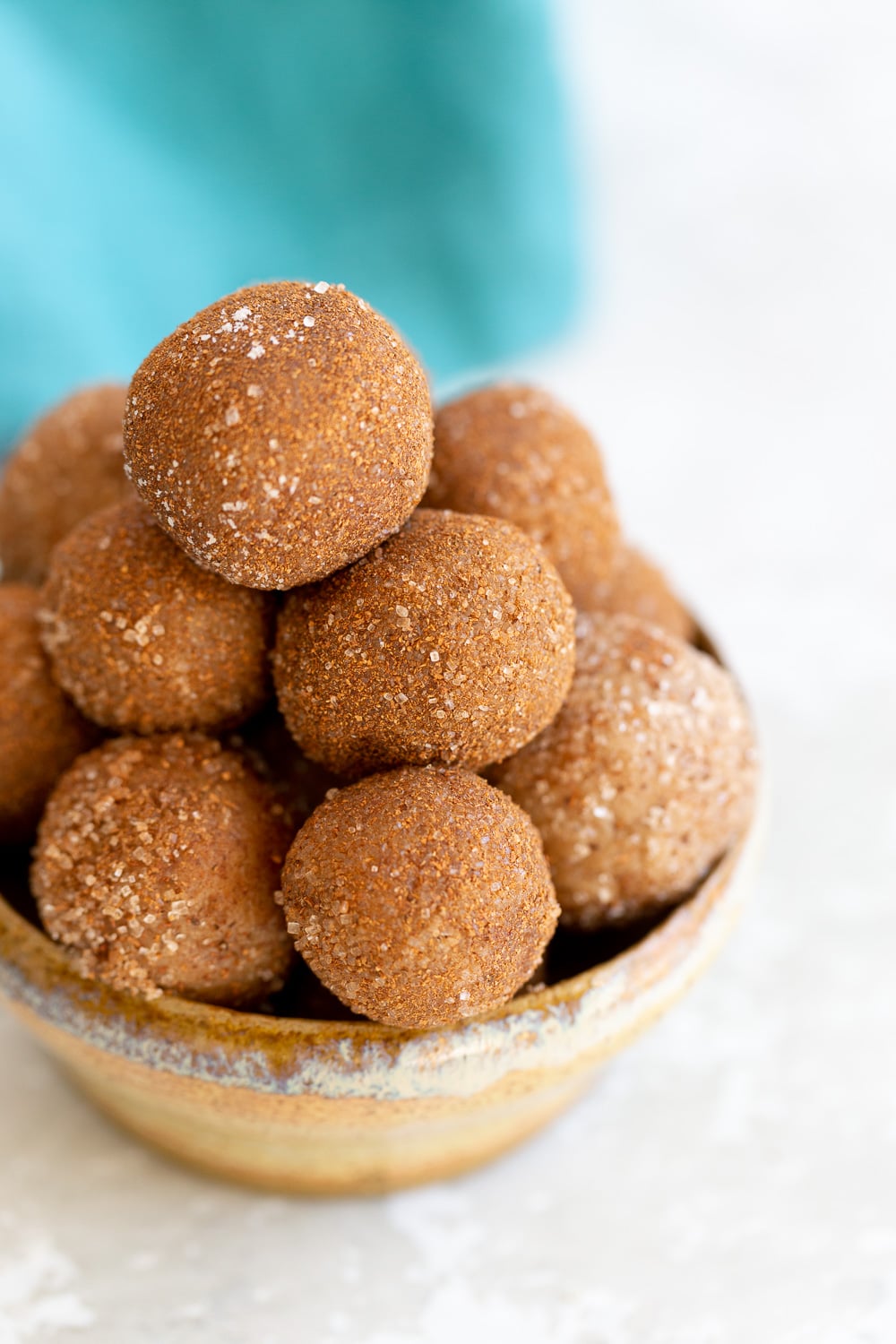Vegan Snickerdoodle bites Vegan Snickerdoodle Snack Bites rolled in cinnamon sugar stacked in a small clay bowl