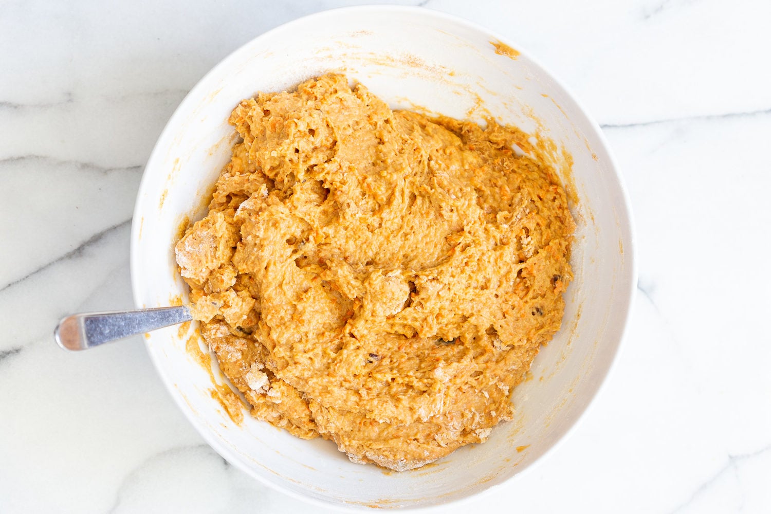 vegan carrot bread stiff vegan carrot bread batter in a mixing bowl with a spoon