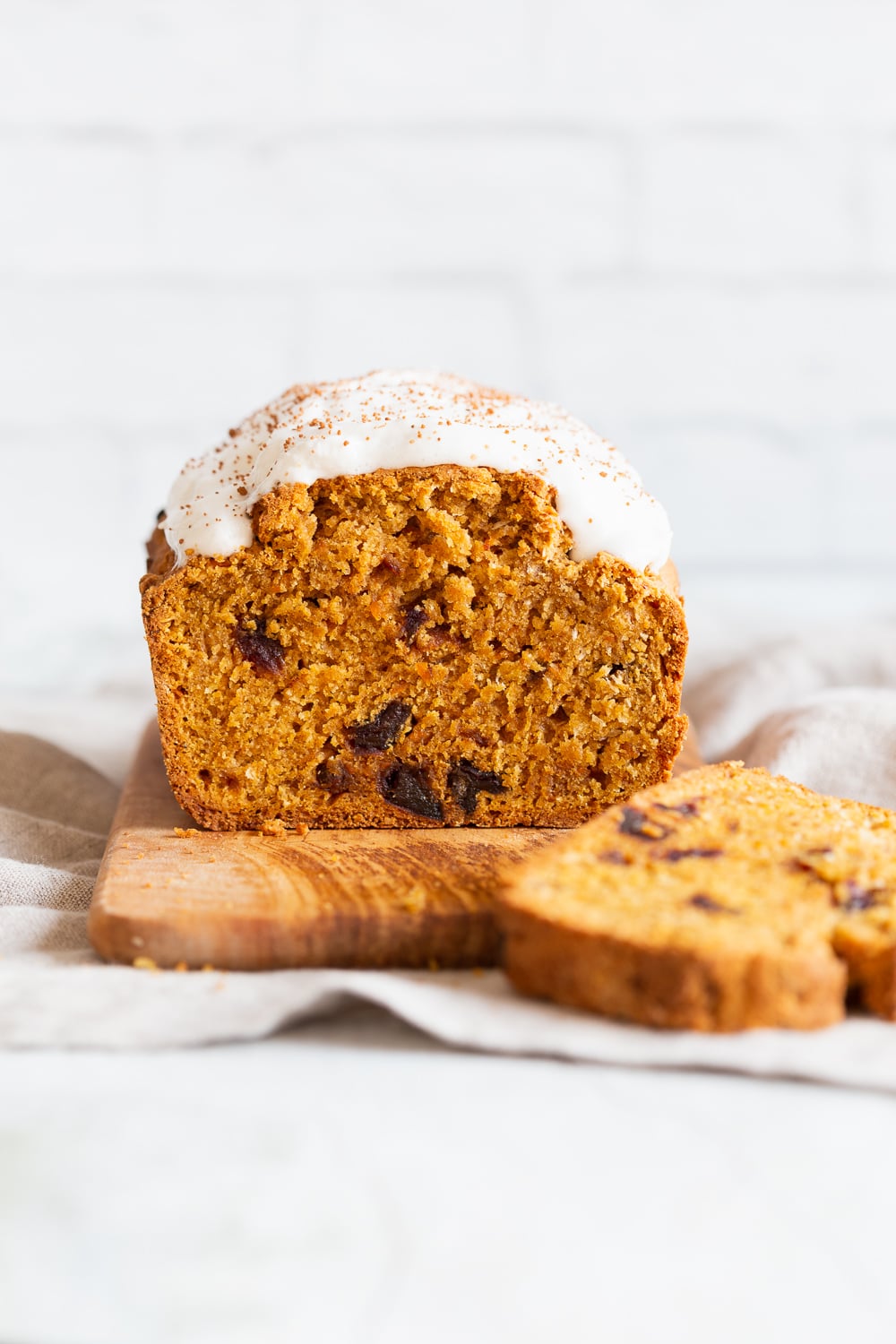 vegan carrot bread side view of a loaf of vegan pumpkin carrot bread with dairy-free icing