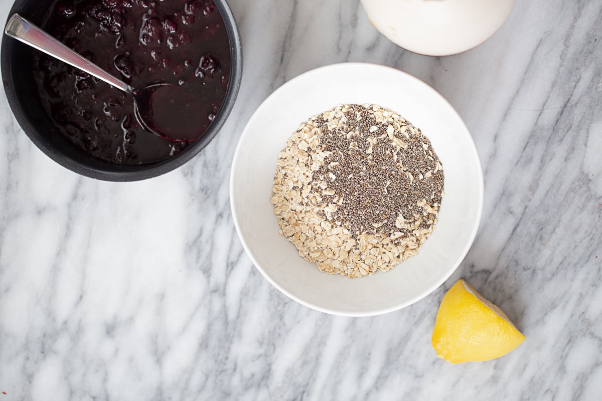 overhead shot of two bowls, one with oats and chia seeds, one with blueberry compote
