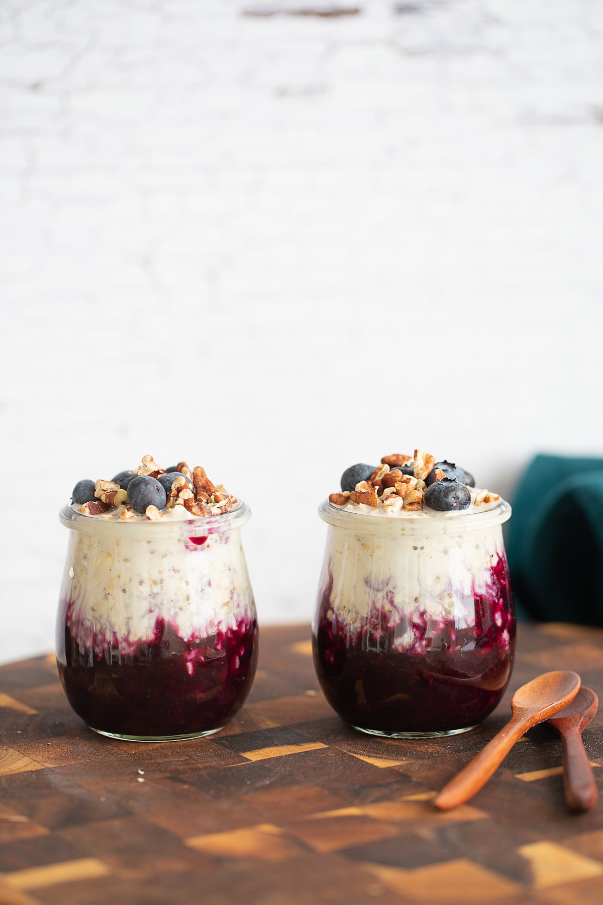 side view of two jars of blueberry overnight oats on a wooden board