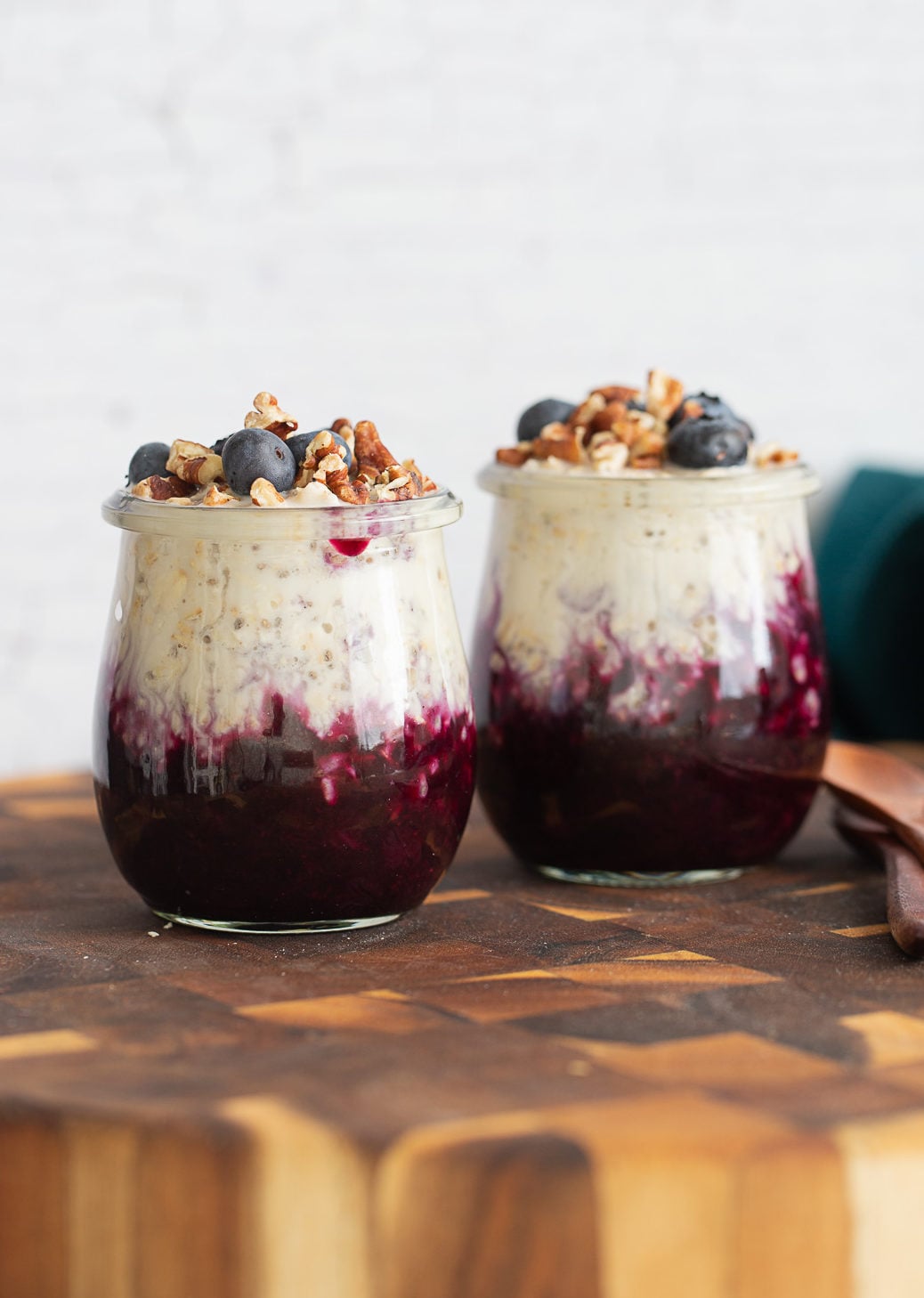blueberry muffin overnight oats in small mason jars topped with chopped pecans and blueberries