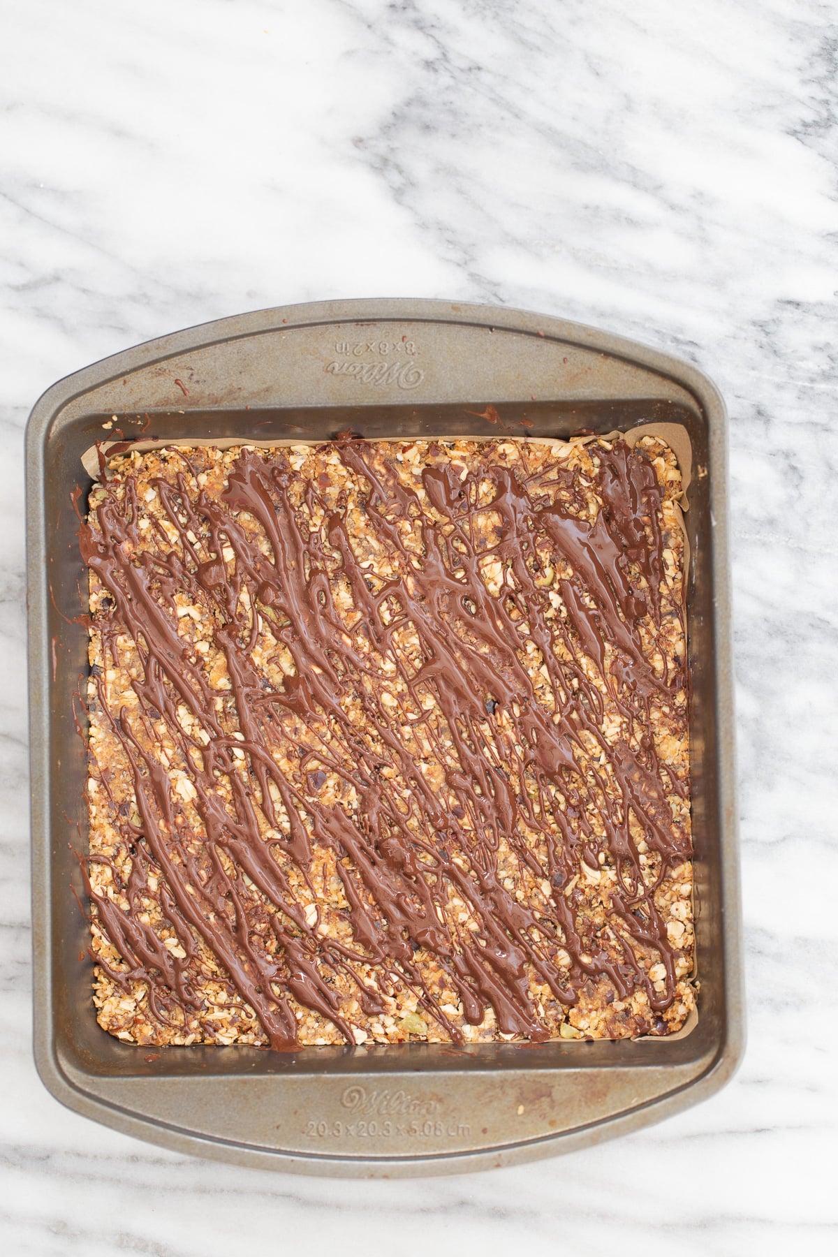 vegan date bars overhead shot of a casserole dish with vegan coconut caramel date bars drizzled with melted chocolate