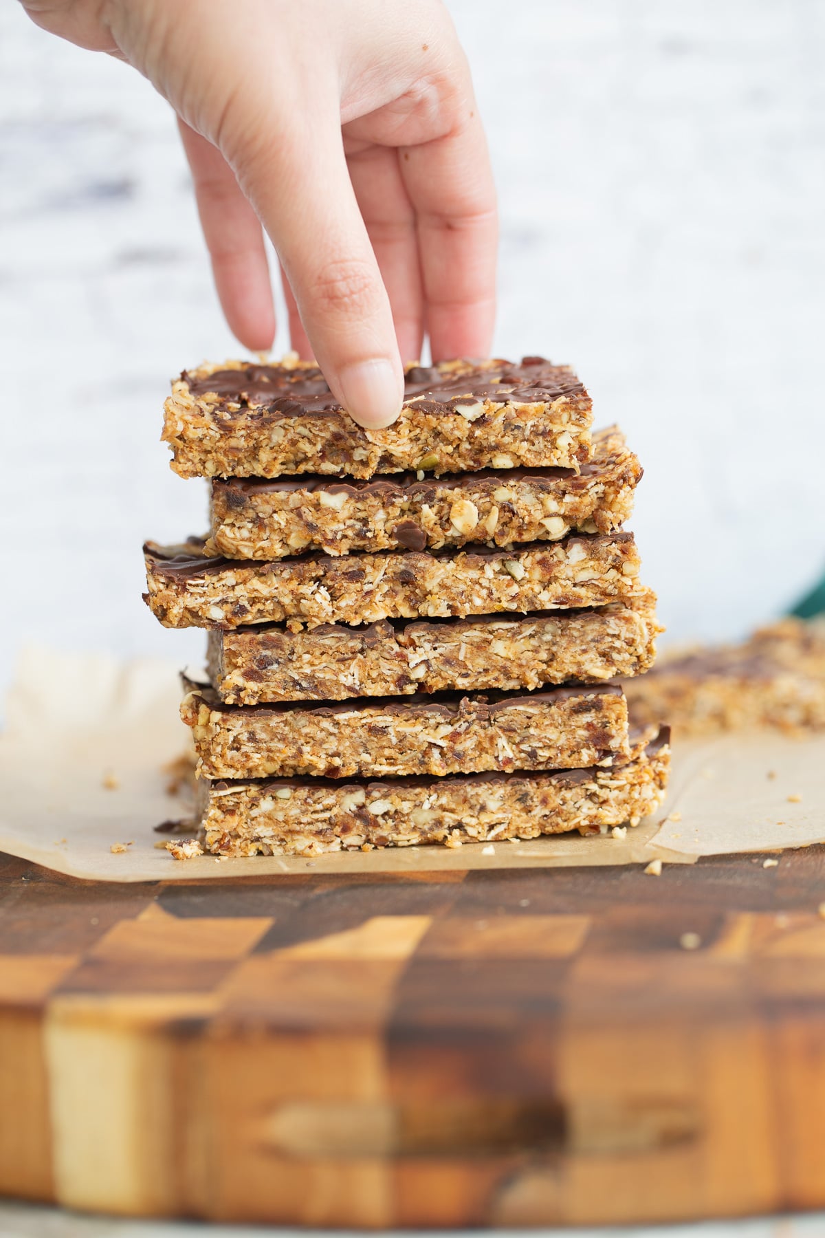 vegan date bars a hand reaching for a vegan date bar on top of a stack of vegan snack bars