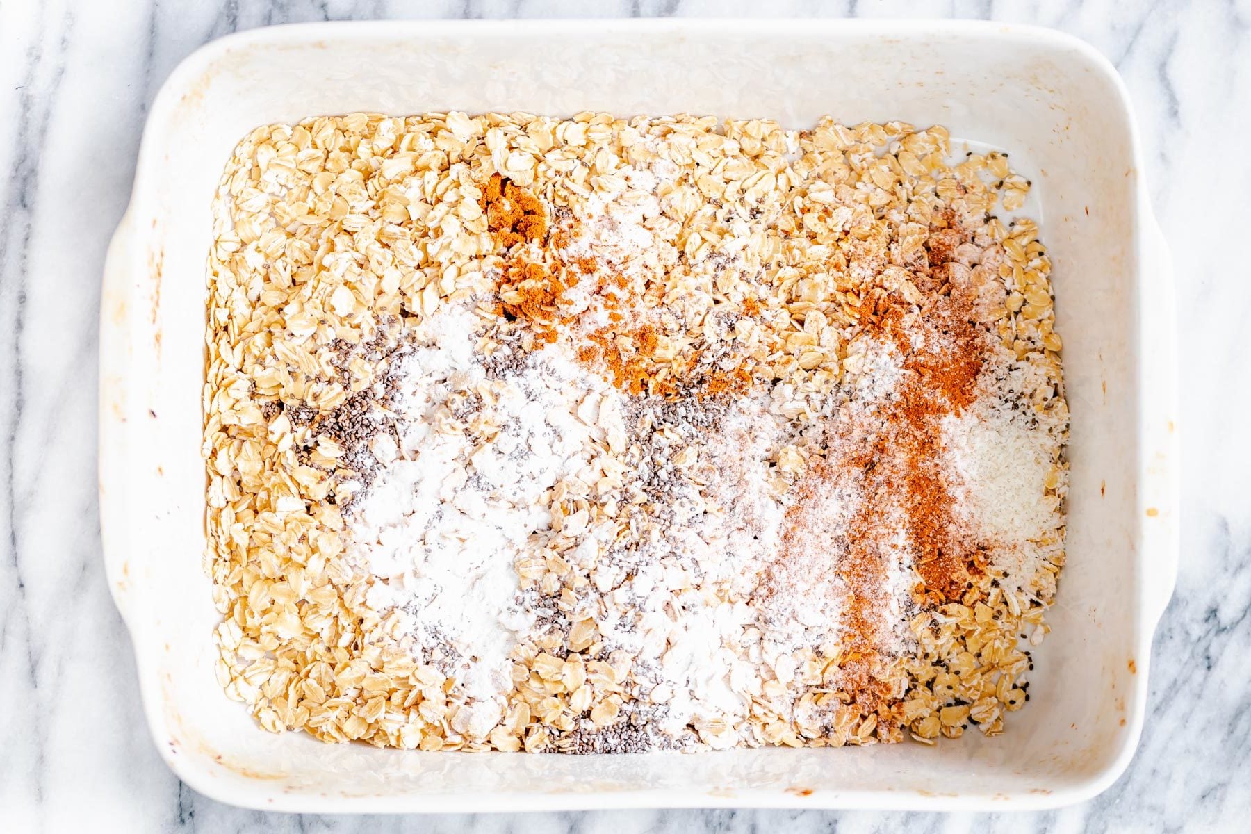ingredients for apple pie baked oatmeal being mixed in a casserole dish