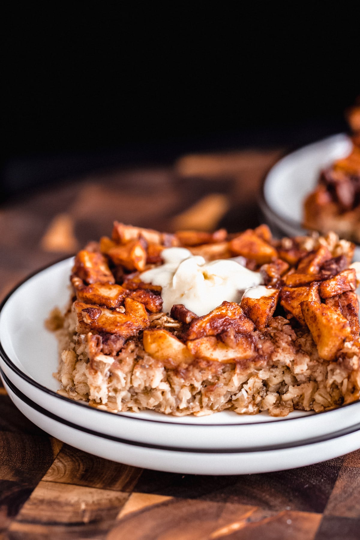 close up of a square of apple pie baked oatmeal on a white cake plate