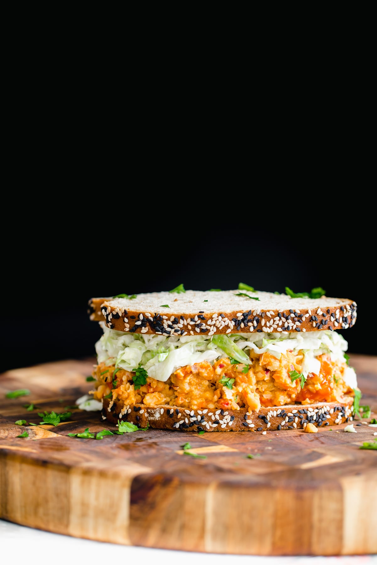 chickpea salad sandwich side view of vegan buffalo chickpea salad sandwich on a wooden board