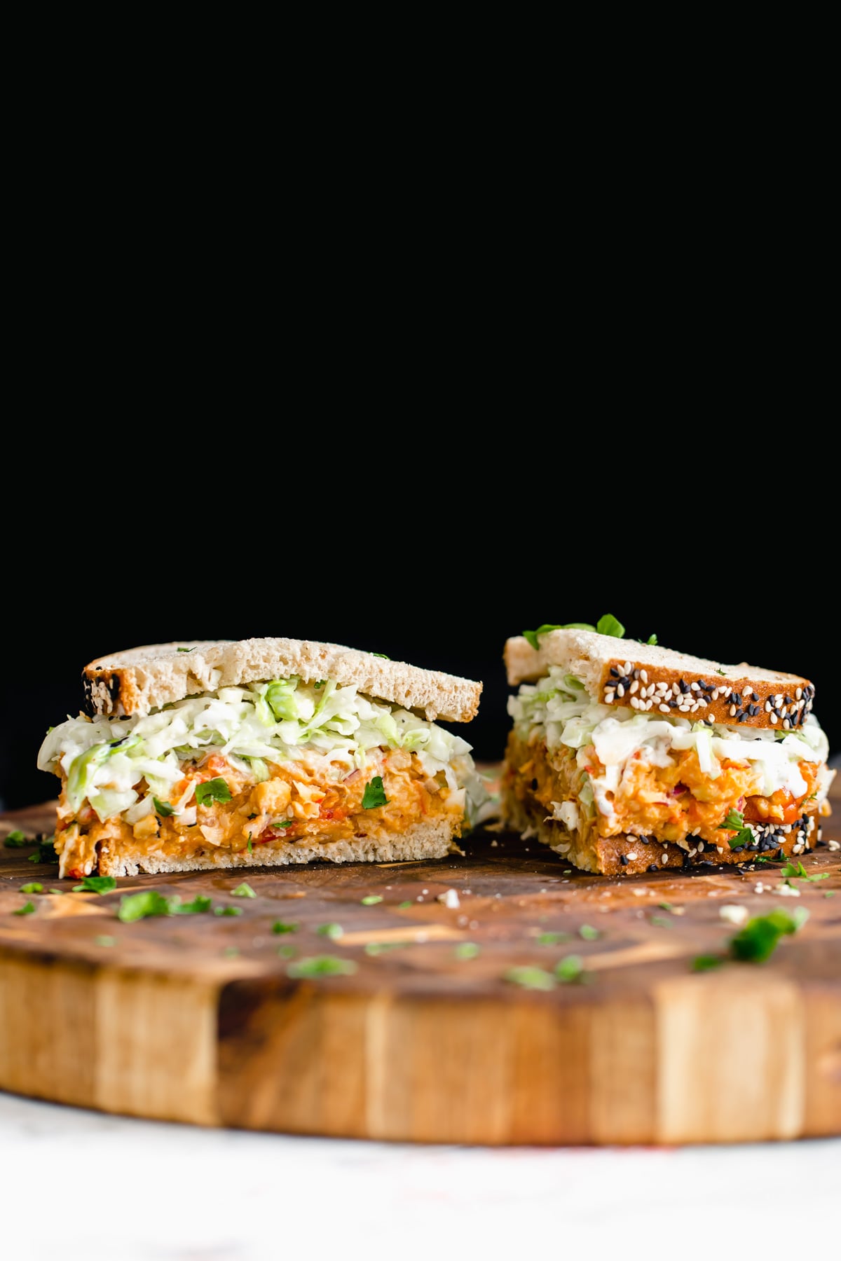 chickpea salad sandwich a halved chickpea salad sandwich on a wooden board