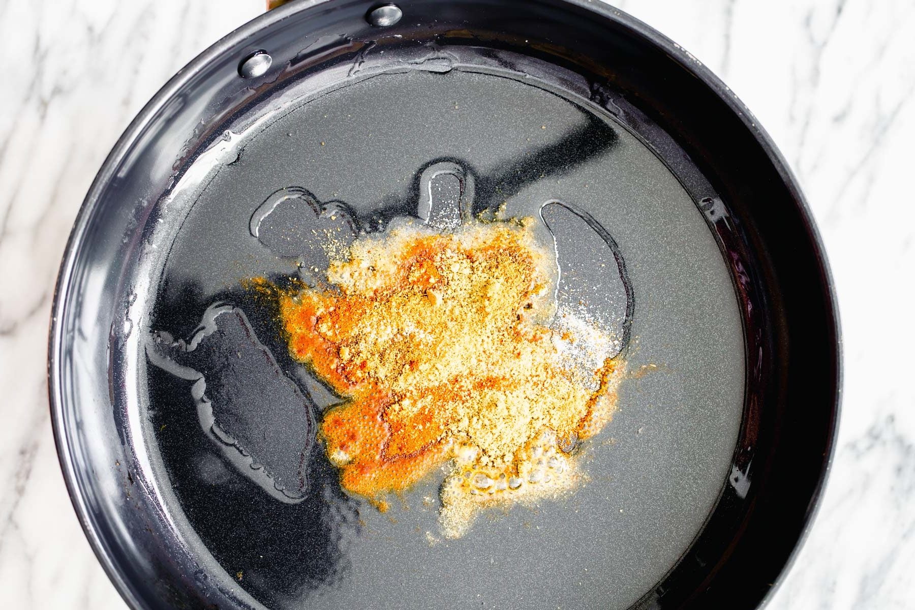 pumpkin curry spices being added to hot oil for tempering