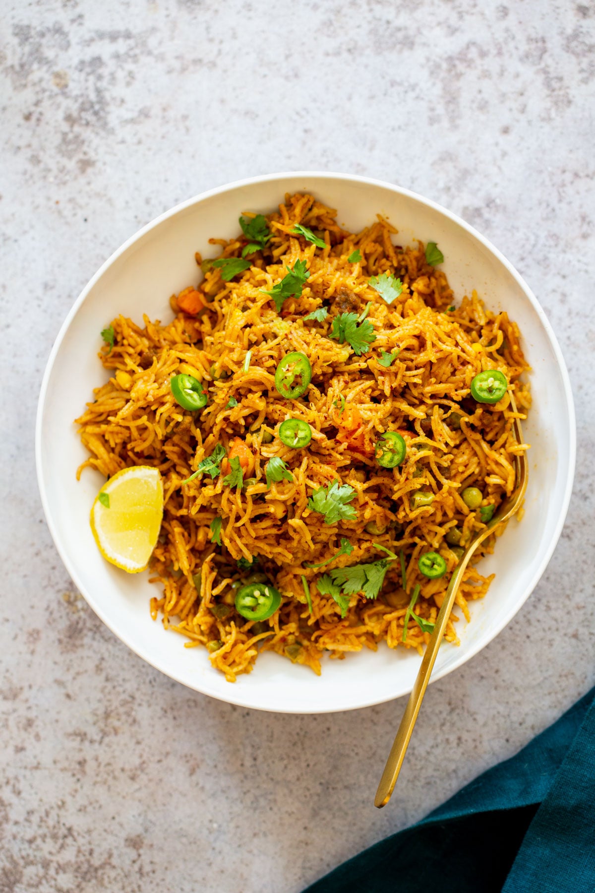 overhead shot of a plate of vegan pumpkin fried rice served with lime and sliced jalapenos