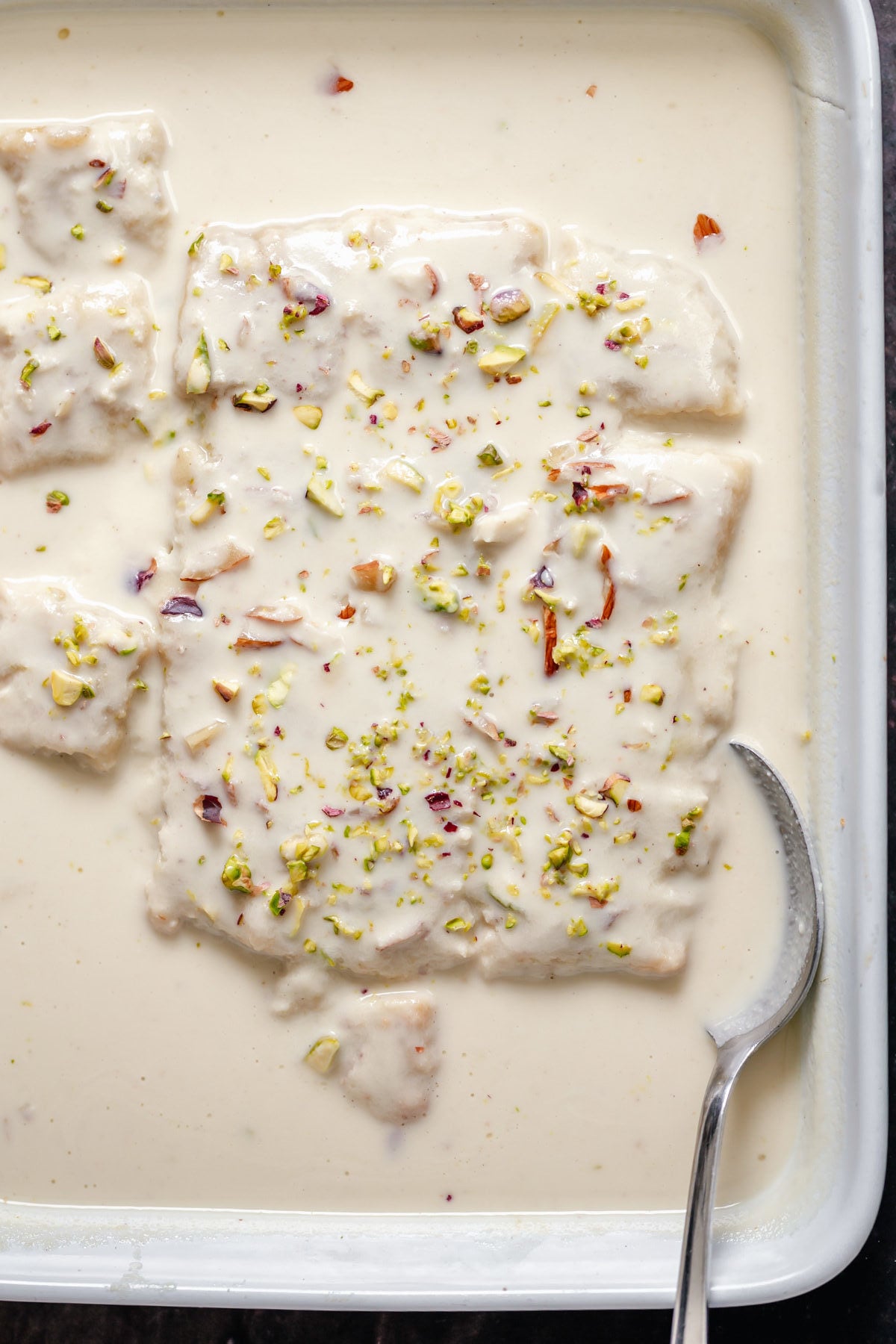 rasmalai cake casserole dish with vegan rasmalai cake with a spoon