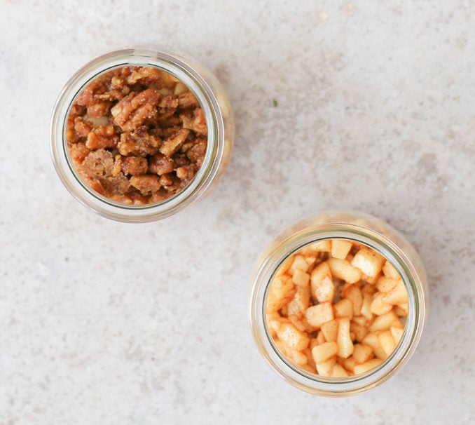 apple pie overnight oats two small dessert glasses being layers to make apple pie overnight oats