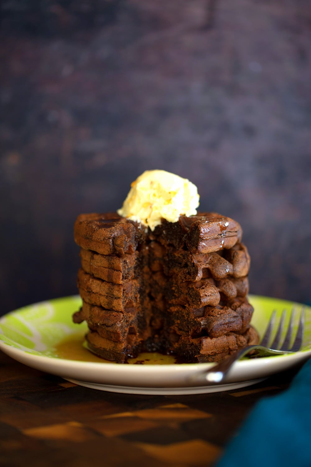 a stack of buckwheat waffles topped with vanilla ice cream with a corner cut out