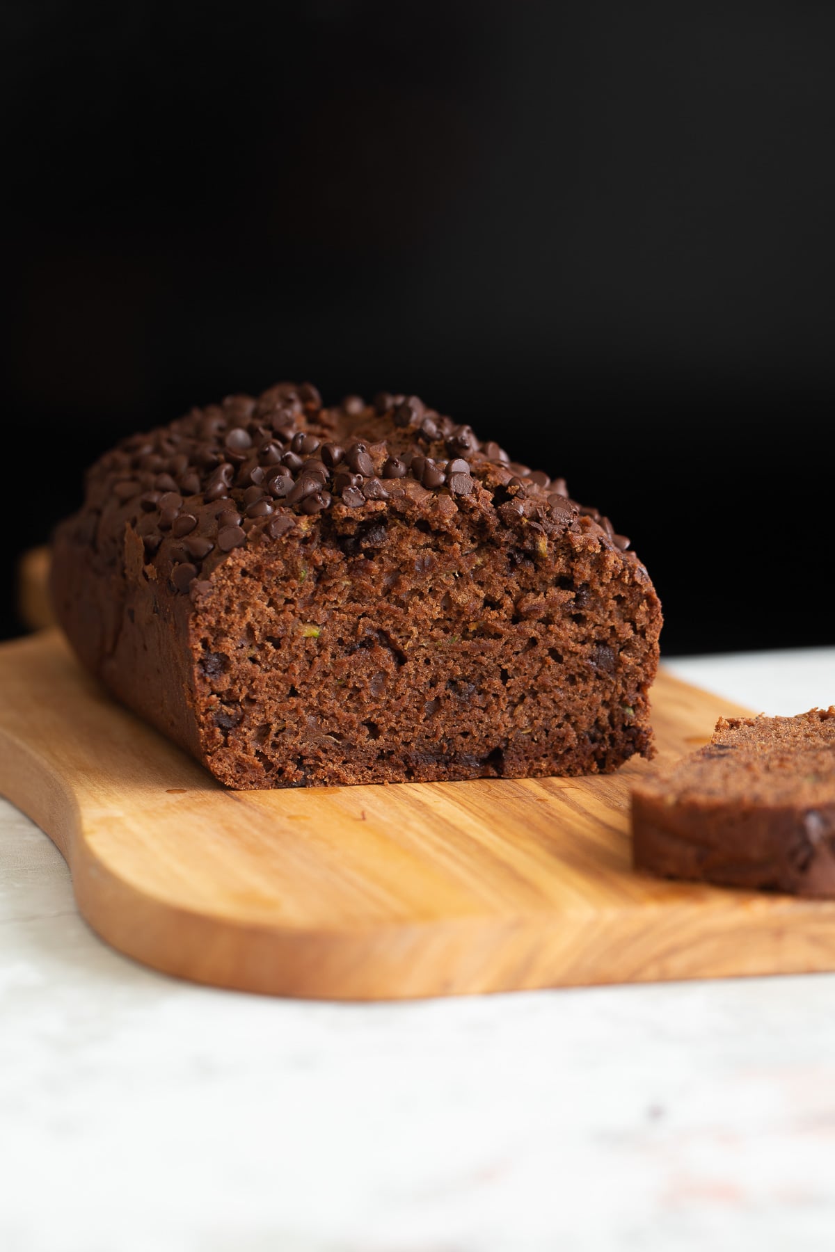 chocolate zucchini bread side view of a loaf of moist vegan chocolate zucchini bread with one slice cut