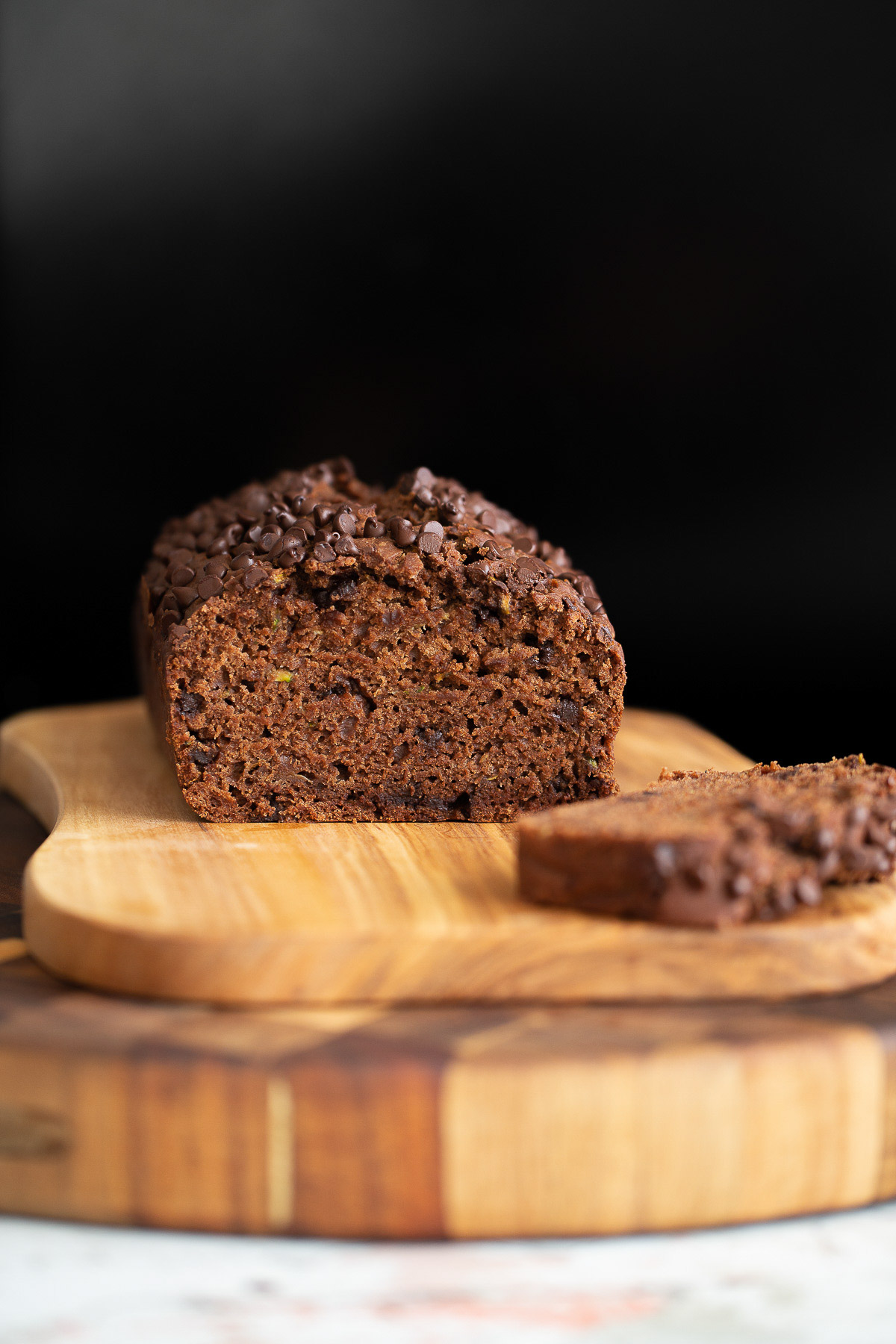 a sliced loaf of chocolate zucchini bread on a wooden chopping board 