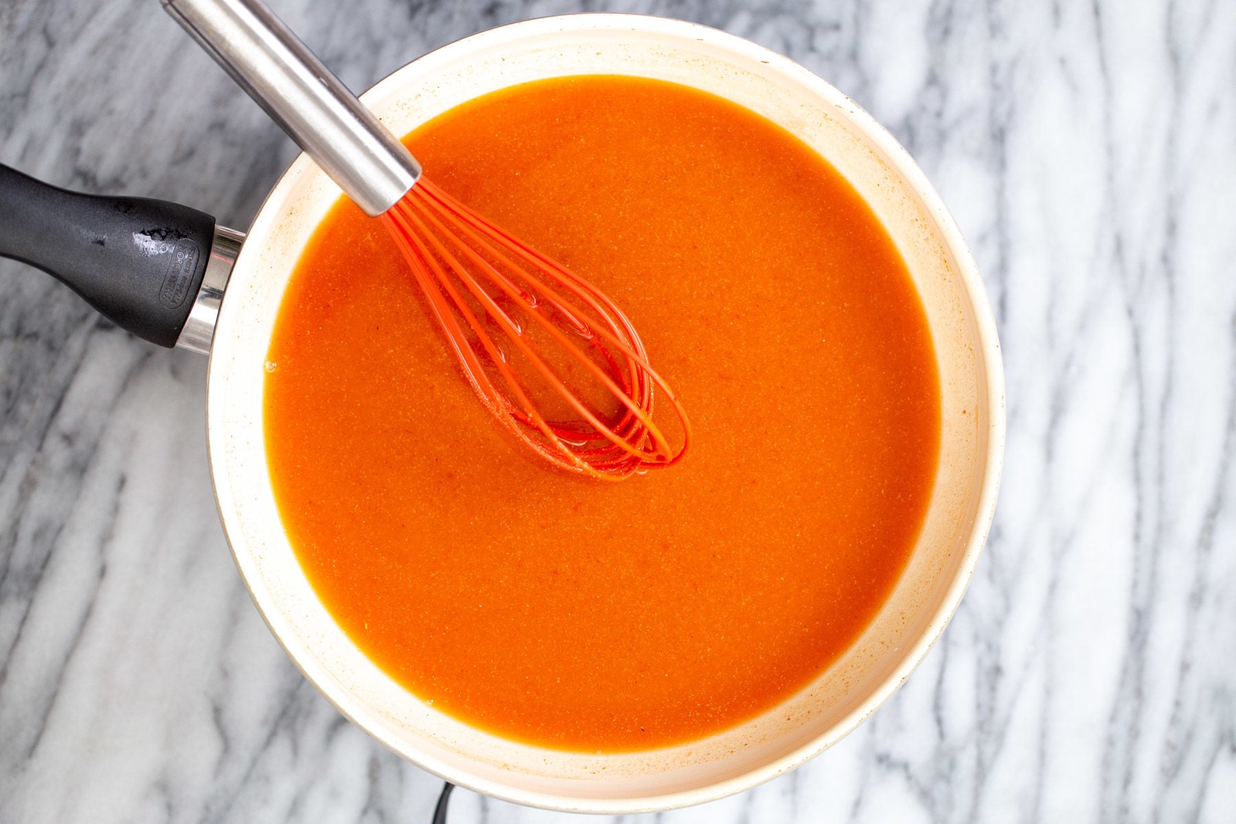 tofu wings firecracker sauce being stirred together in a white saucepan