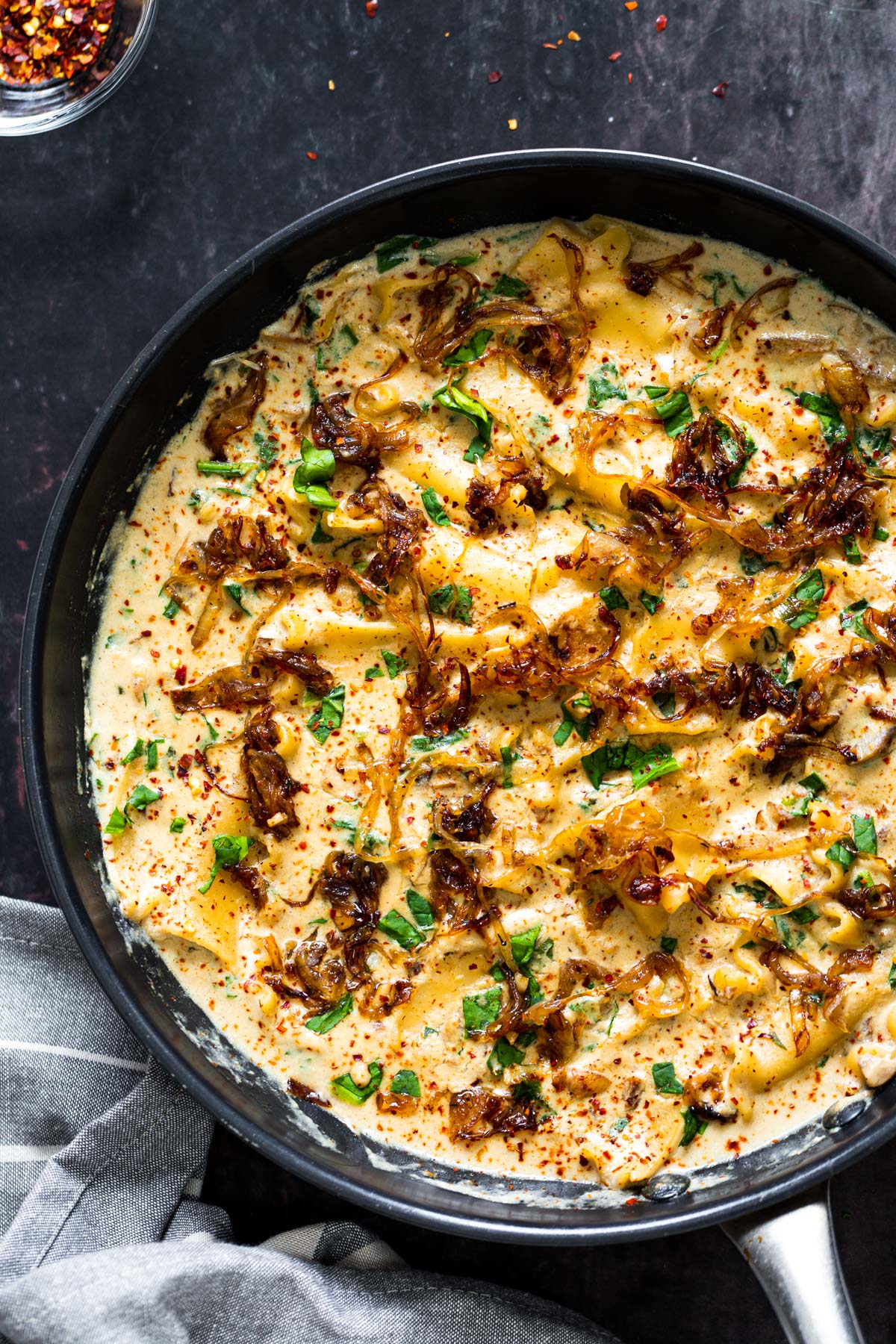 a skillet with vegan French onion skillet lasagna topped with caramelized onions
