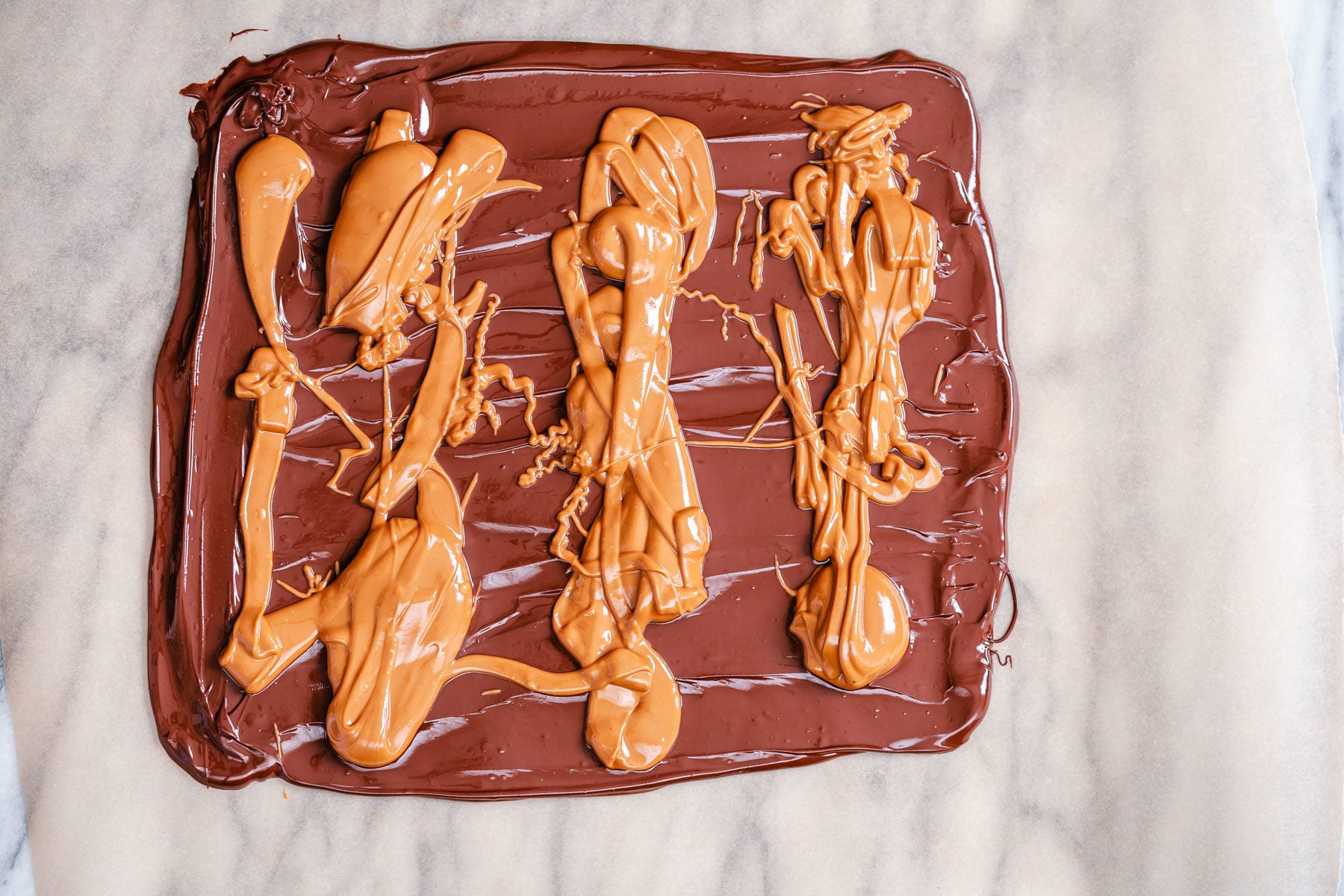 peanut butter chocolate bark melted peanut butter being spread on top of melted chocolate to make bark