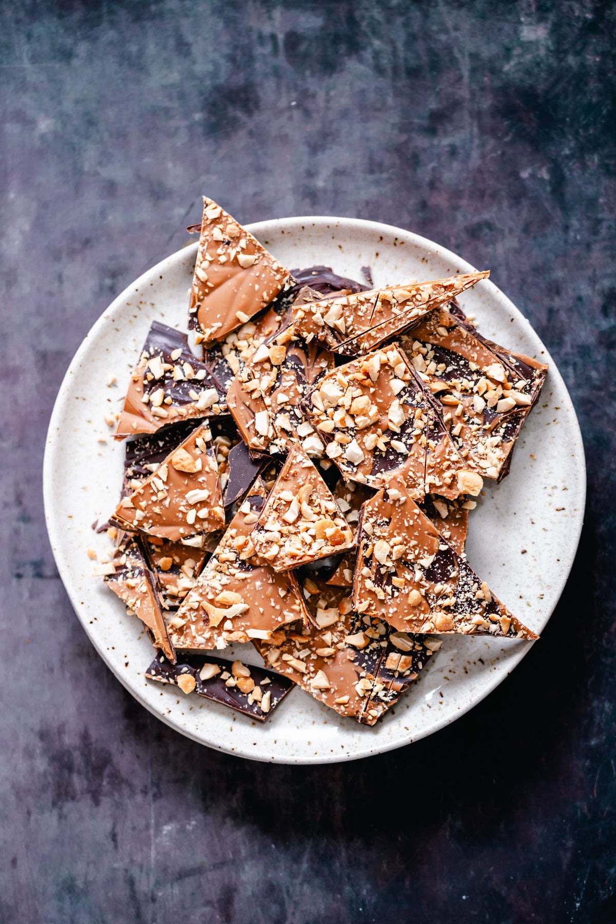 peanut butter chocolate bark vegan dark chocolate and peanut butter bark with chopped peanuts on a white plate