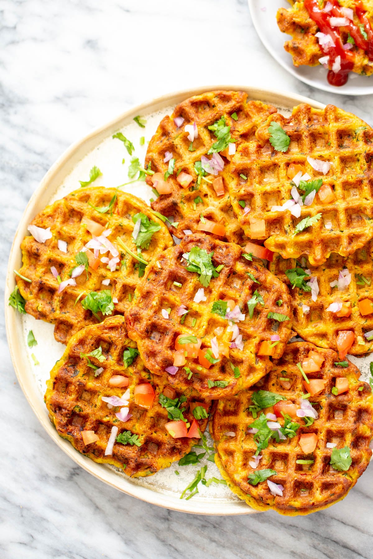 chickpea flour waffles overhead shot of a plate of crispy pakora chickpea flour waffles topped with fresh onions and herbs