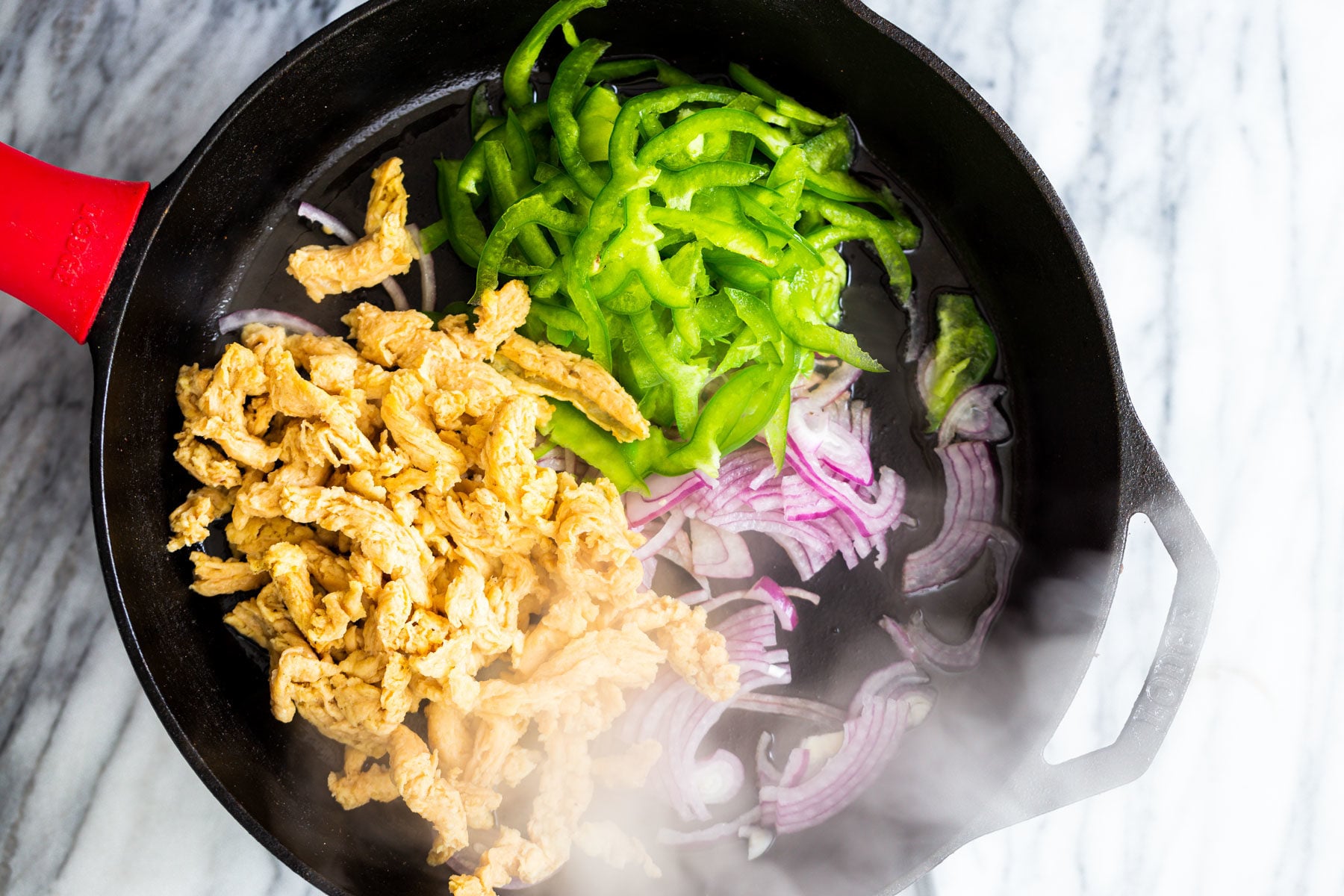 vegan skillet enchiladas onions bell peppers and soy curls sauteeing in a black skillet
