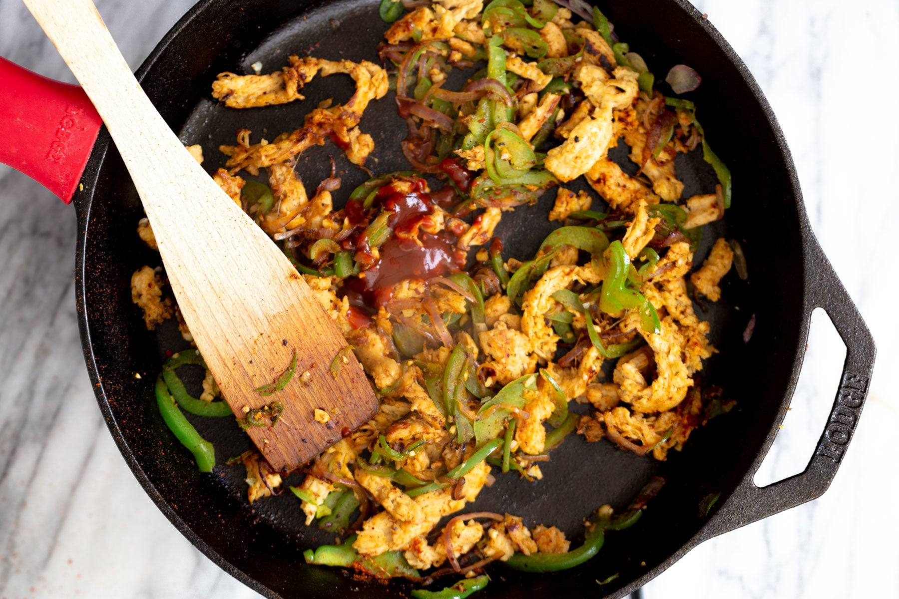 chile in adobo being added to soy curls and sauteed veggies in a black skillet