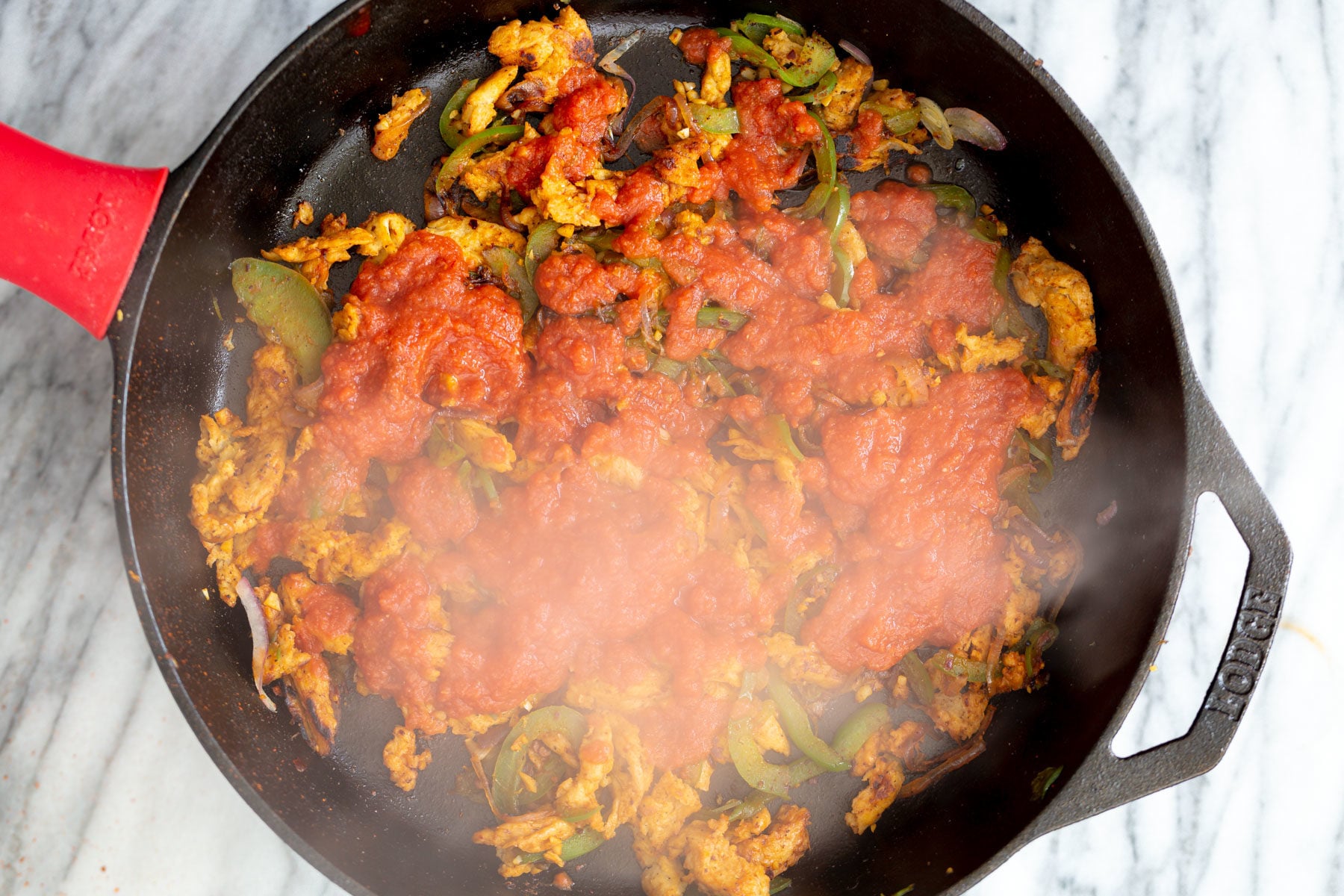 vegan skillet enchiladas tomato sauce being added to skillet with veggies and soy curls for making Mexican enchiladas