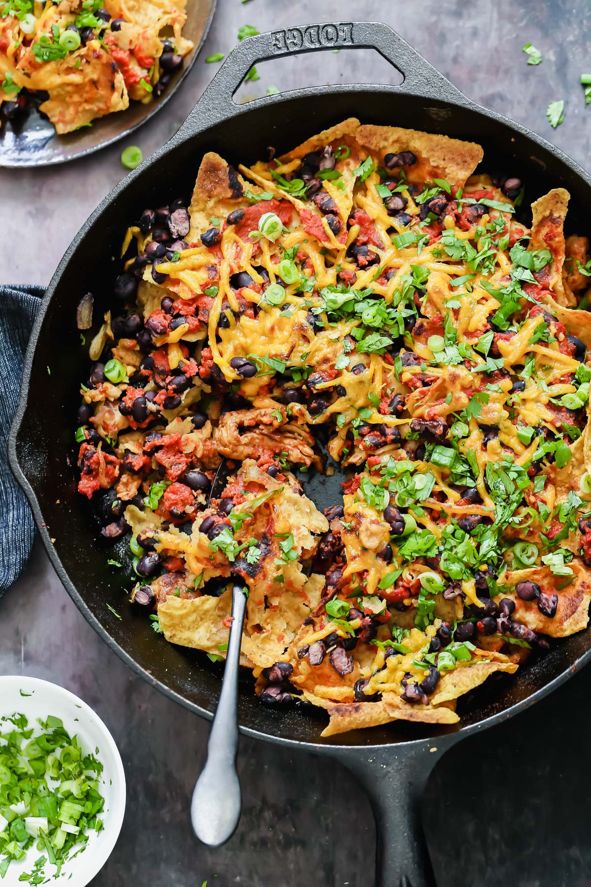 skillet enchiladas overhead shot of a vegan skillet nachos topped with vegan cheese shreds and green onions