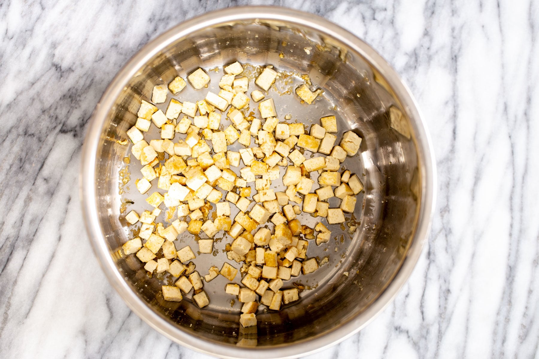 tofu cubes being fried in a pot